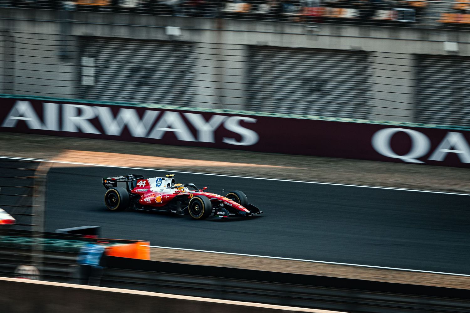 Red Bull Formula 1 car racing past Qatar Airways signage on circuit track.