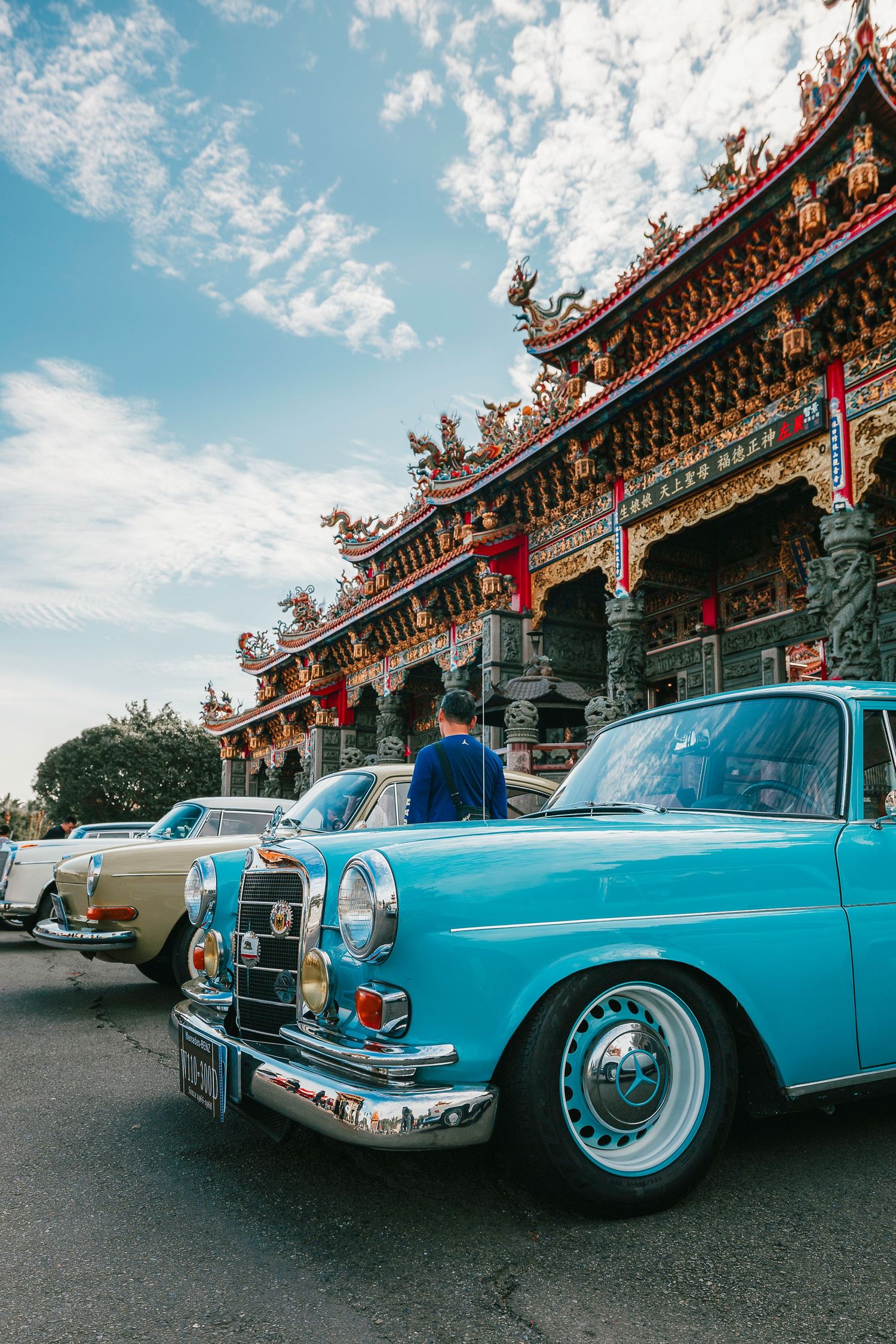 Vintage turquoise Mercedes-Benz classic car parked outside ornate traditional Taiwanese temple.
