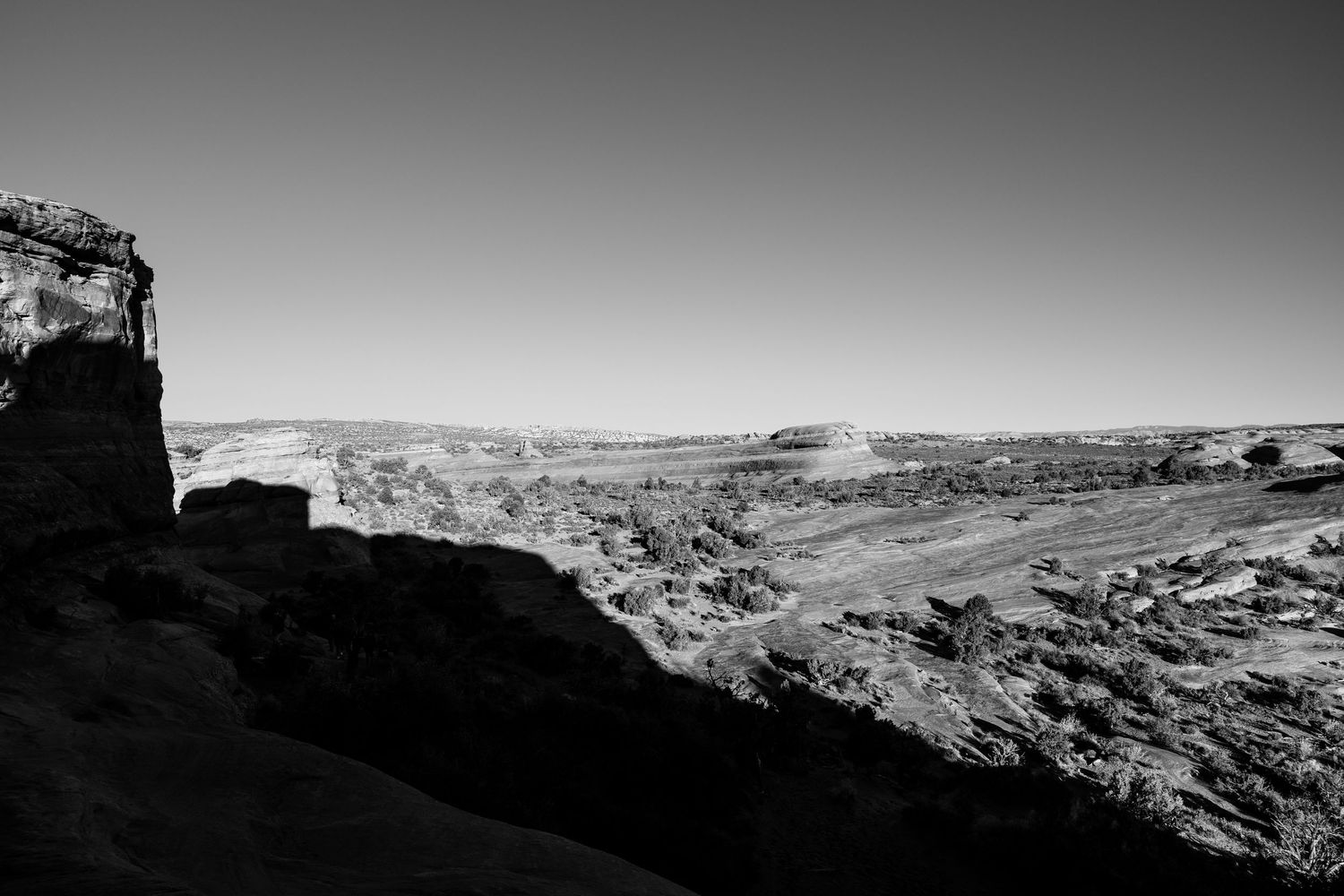 Black and white panoramic view of vast canyon landscape under clear sky.