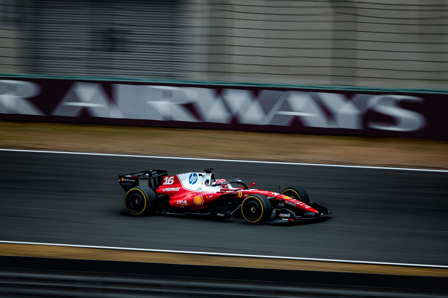 Ferrari Formula 1 car speeding past Qatar Airways advertisement board on racing circuit.