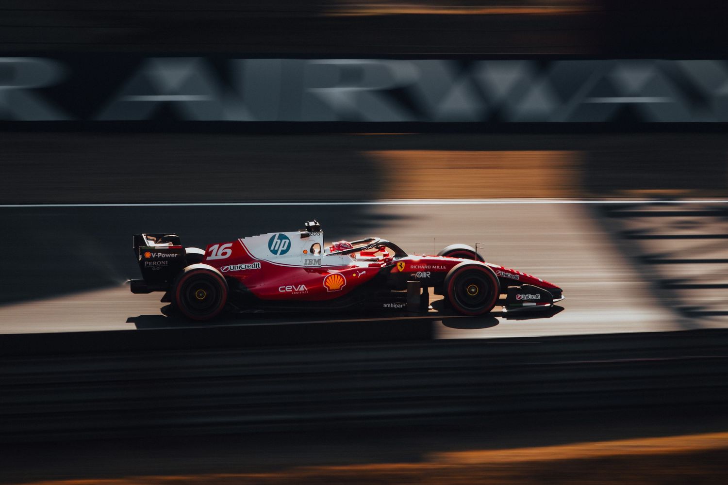 Ferrari F1 car number 16 racing at high speed on a Formula 1 circuit with motion blur background.