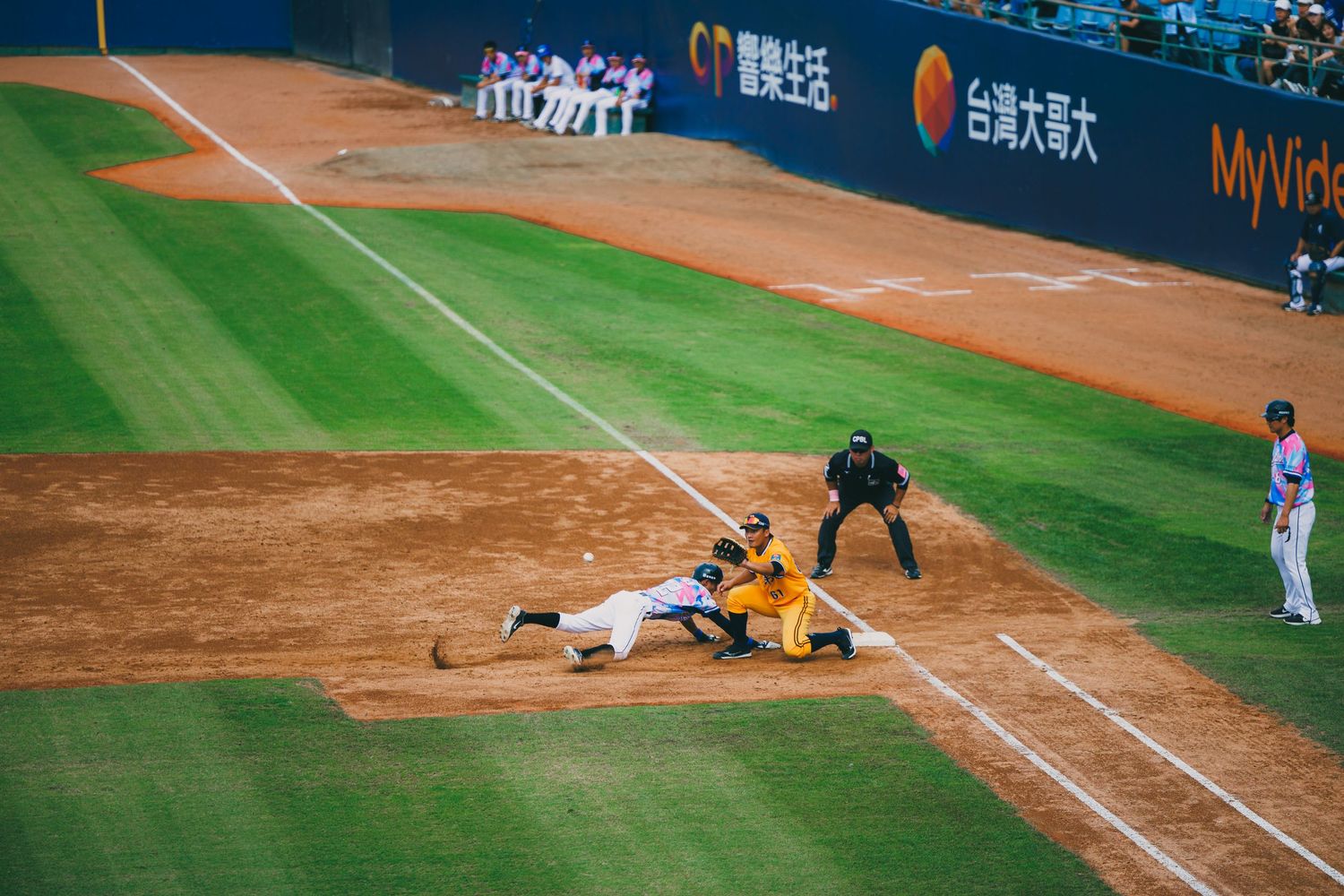 Baseball player sliding into home plate as fielder attempts tag during a professional stadium game.