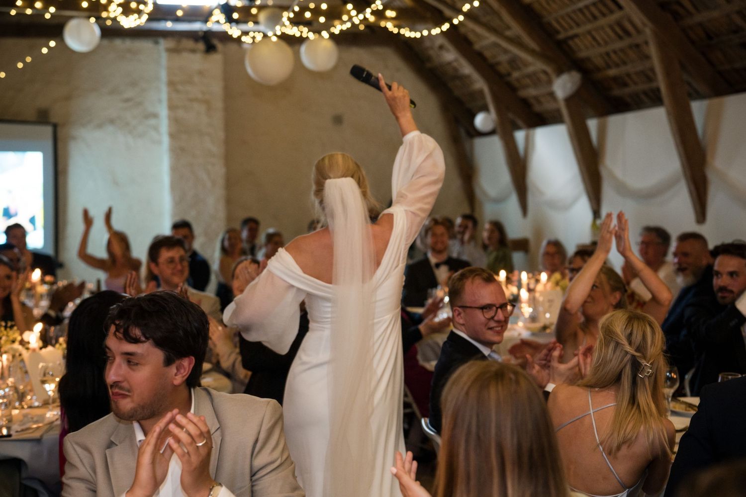 Wedding guests dancing and celebrating on a dance floor decorated with string lights during an indoor reception.