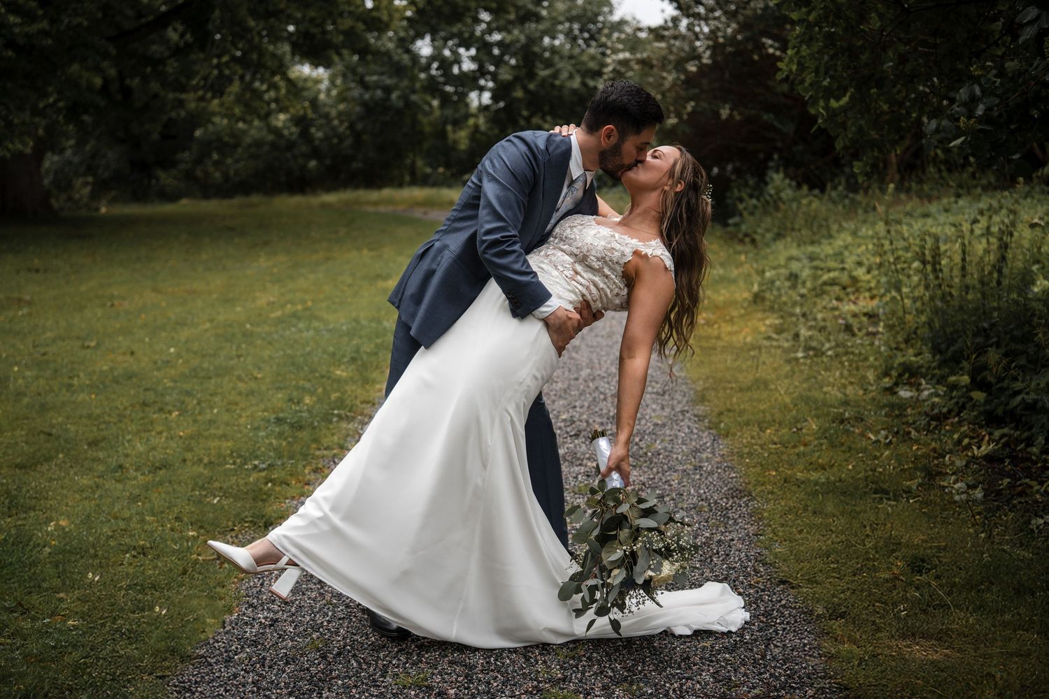 A romantic wedding couple sharing intimate moments and poses in a lush outdoor garden setting.