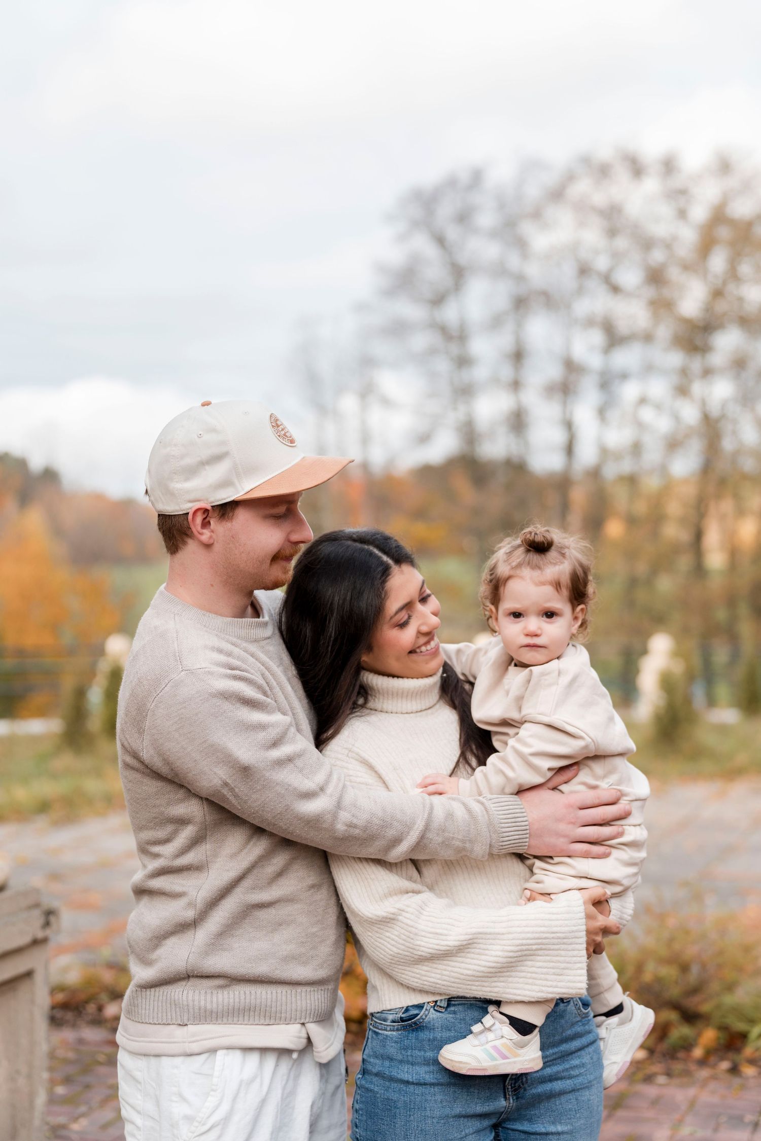 A family shares tender moments together outdoors during autumn, wearing cozy sweaters while embracing.