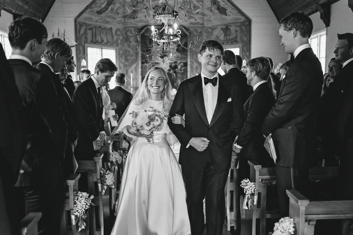 A series of black and white wedding photos showing guests dancing and celebrating at an elegant reception venue.