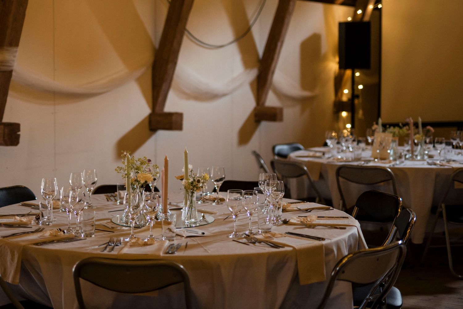 Elegant dining tables set with white linens, glassware and place settings in an upscale restaurant interior.