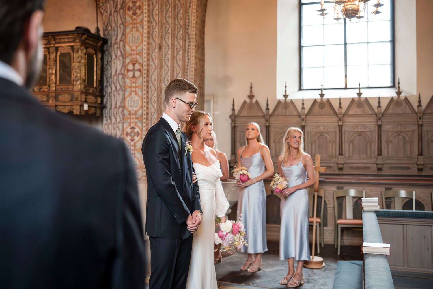A wedding ceremony taking place in a beautiful historic church with ornate stone walls and stained glass windows.