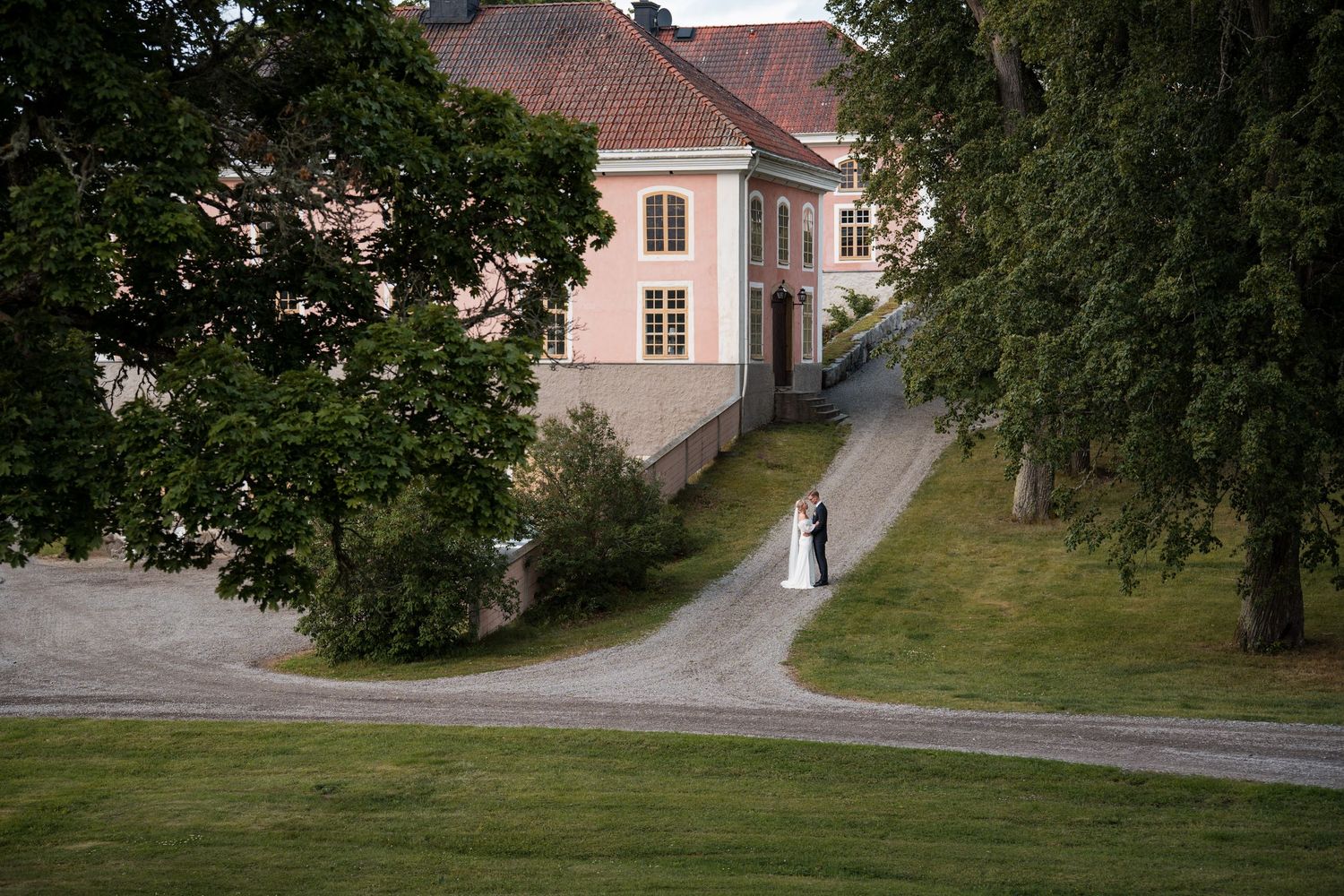 A scenic pathway through a historic estate grounds with traditional architecture and lush greenery.