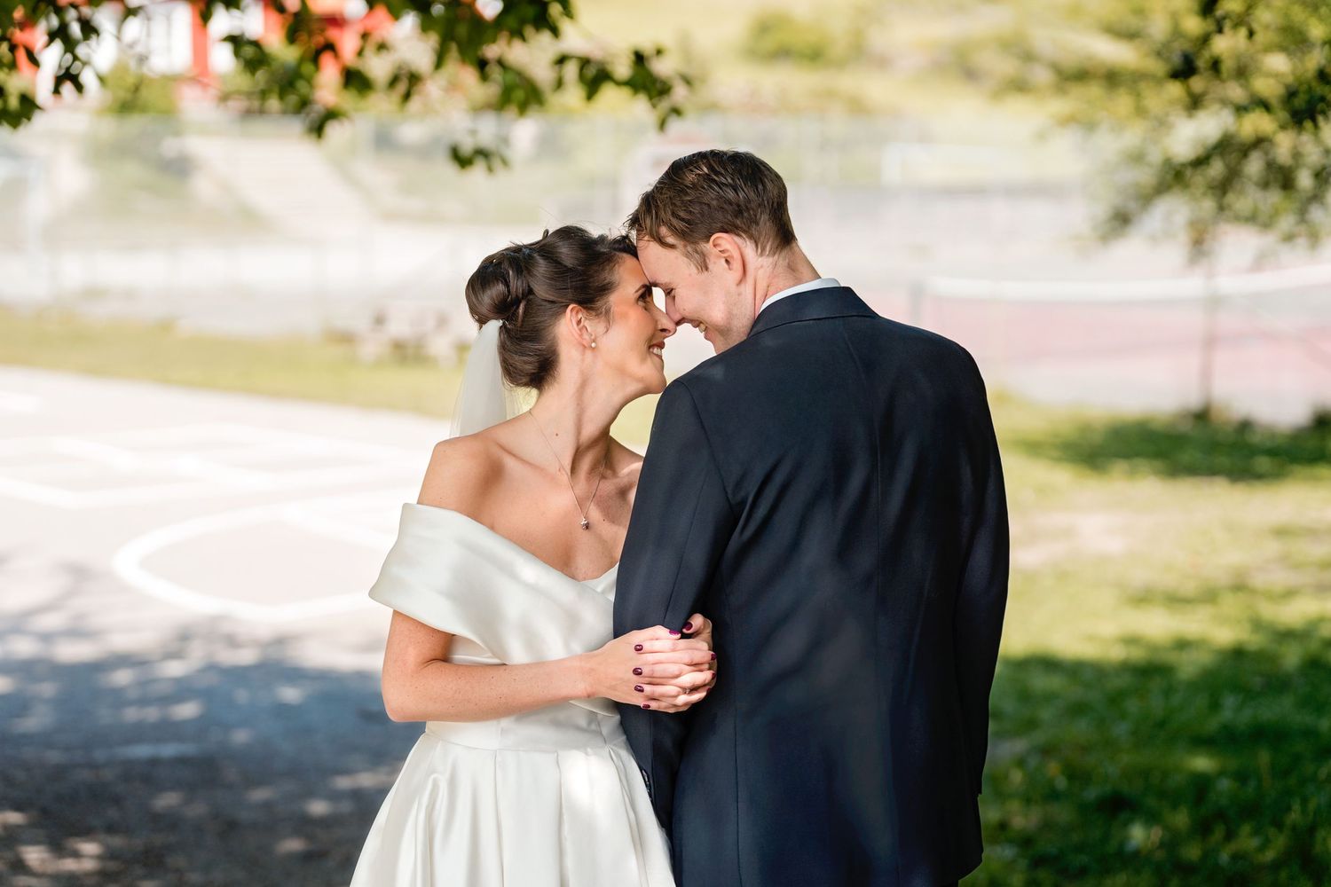 A couple dances together in an outdoor garden setting wearing wedding attire.