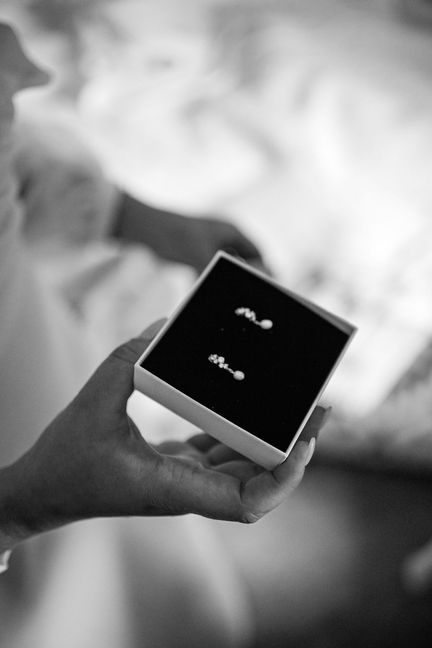 A sequence of black and white images showing hands holding and displaying a small jewelry box with a ring inside.