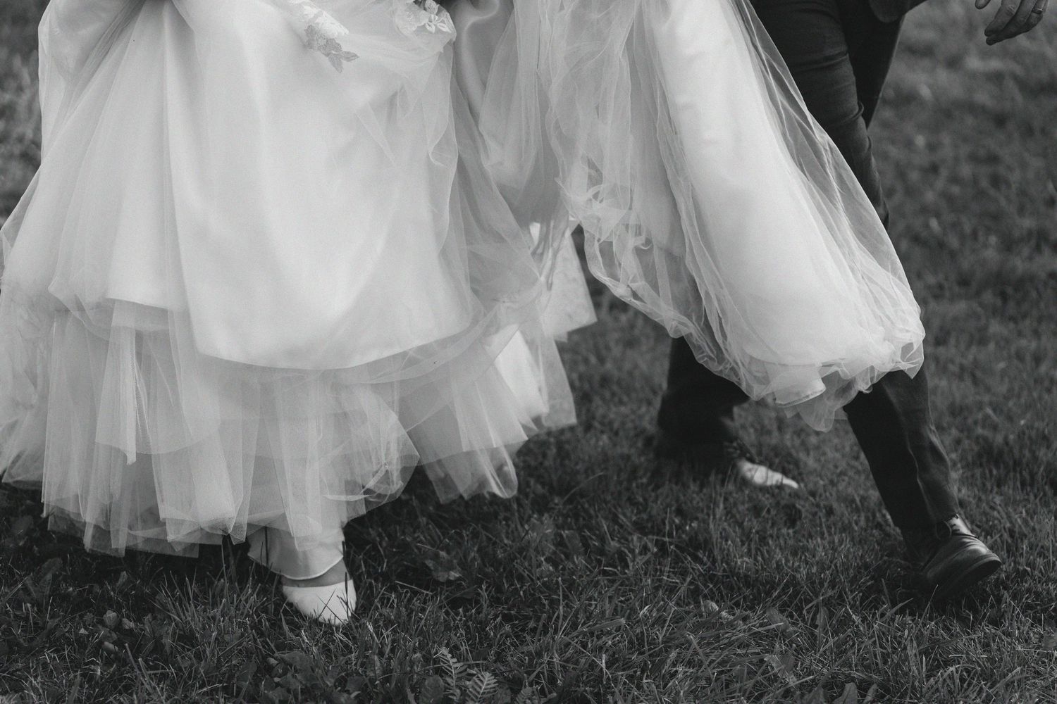 Ethereal white wedding dresses flowing in motion against a grassy outdoor setting.