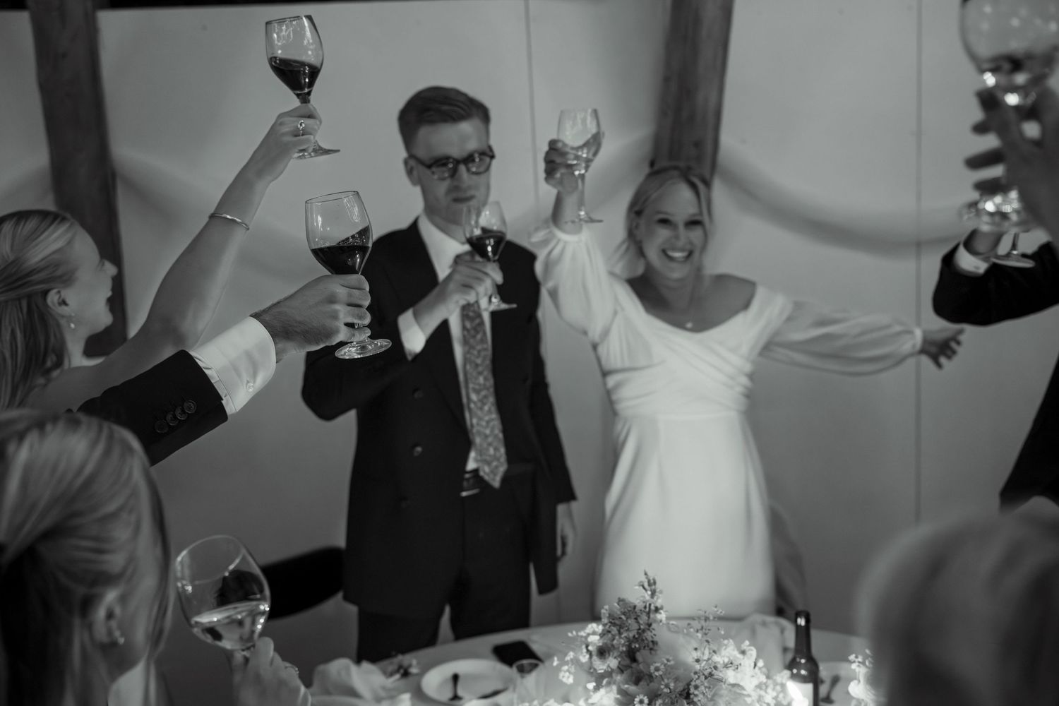 Wedding guests raise wine glasses in a celebratory toast during an elegant reception.