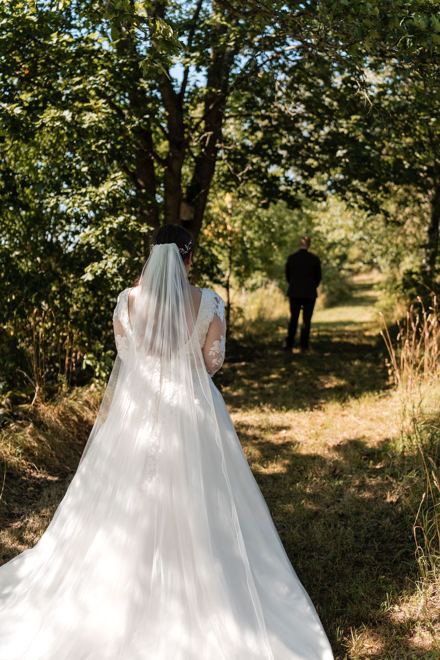 Sunlit wedding gown with flowing tulle skirt captured in a dreamy orchard setting.