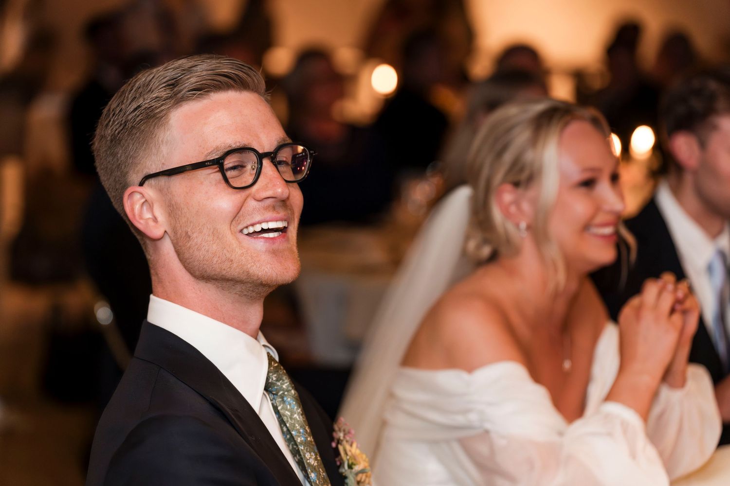 Wedding guests share joyful laughter and smiles during a candid reception moment.