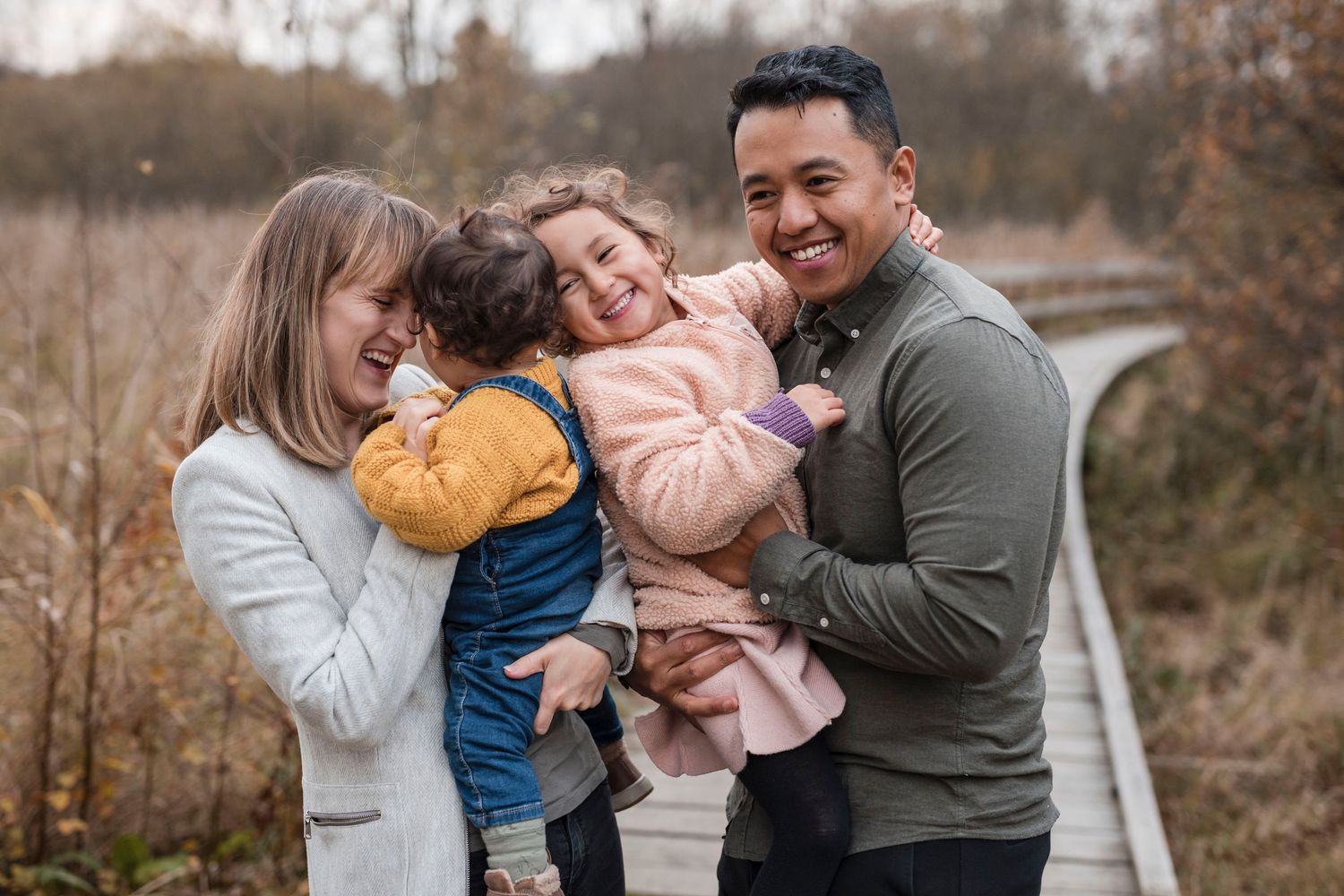 A family shares a joyful moment together on a wooden walkway during autumn.