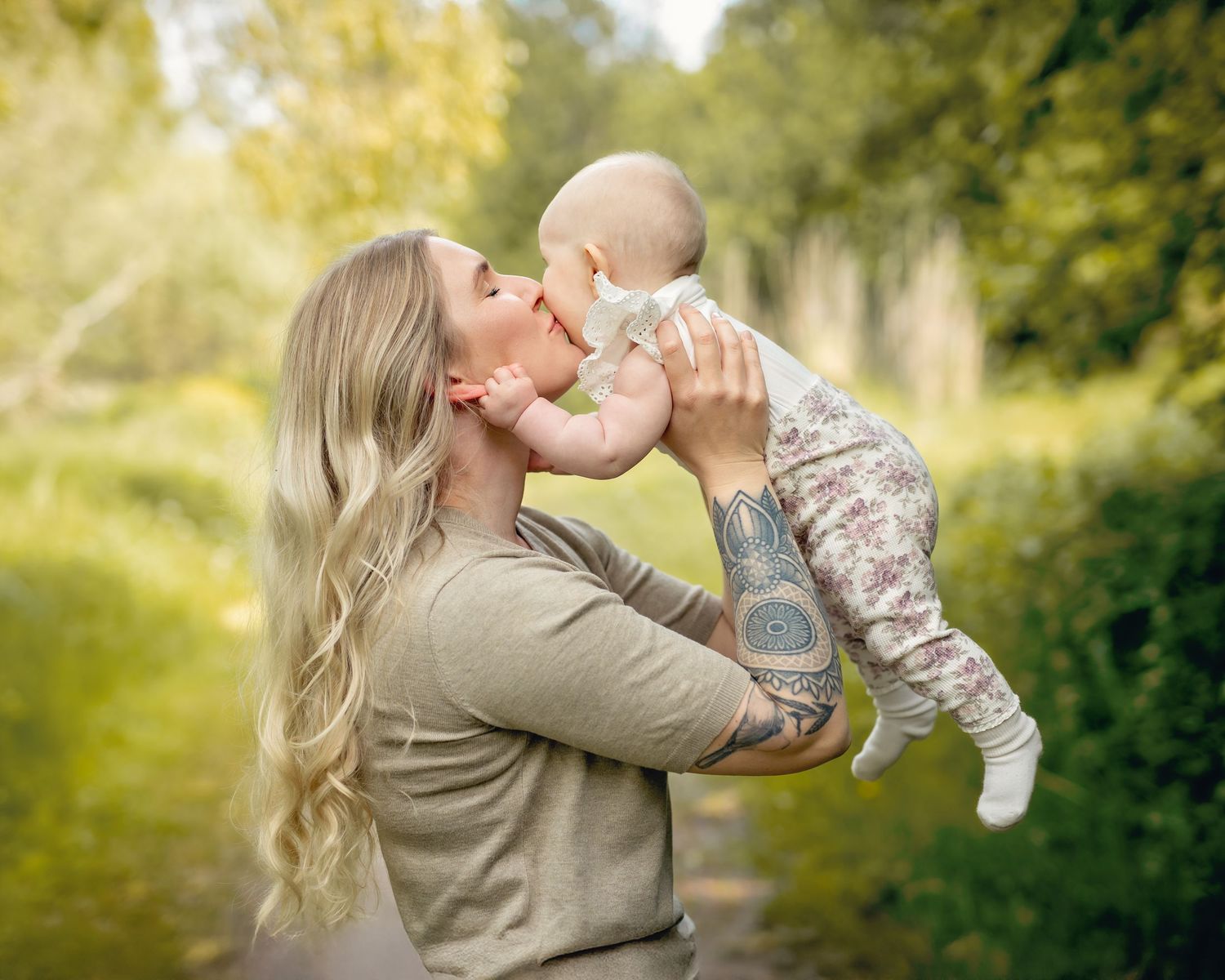 A tender moment shared between parent and child in a sunlit outdoor setting with green foliage in the background.