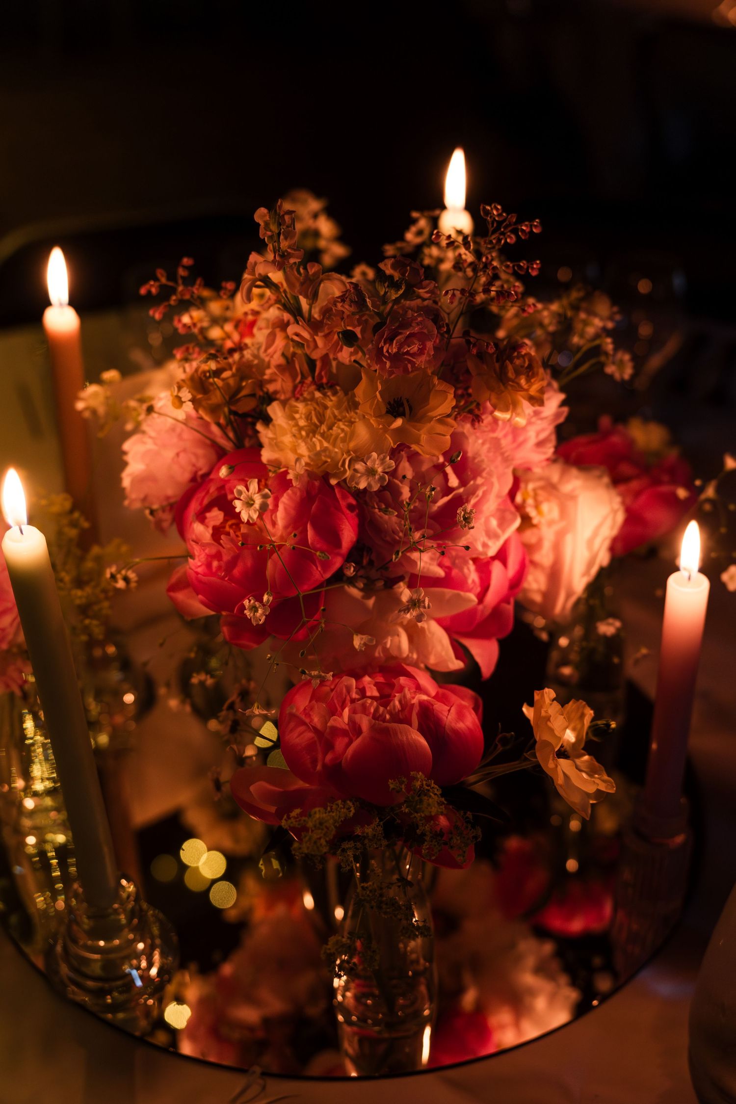 Romantic candlelit table setting with pink floral centerpieces and glowing candles creating an intimate ambiance.