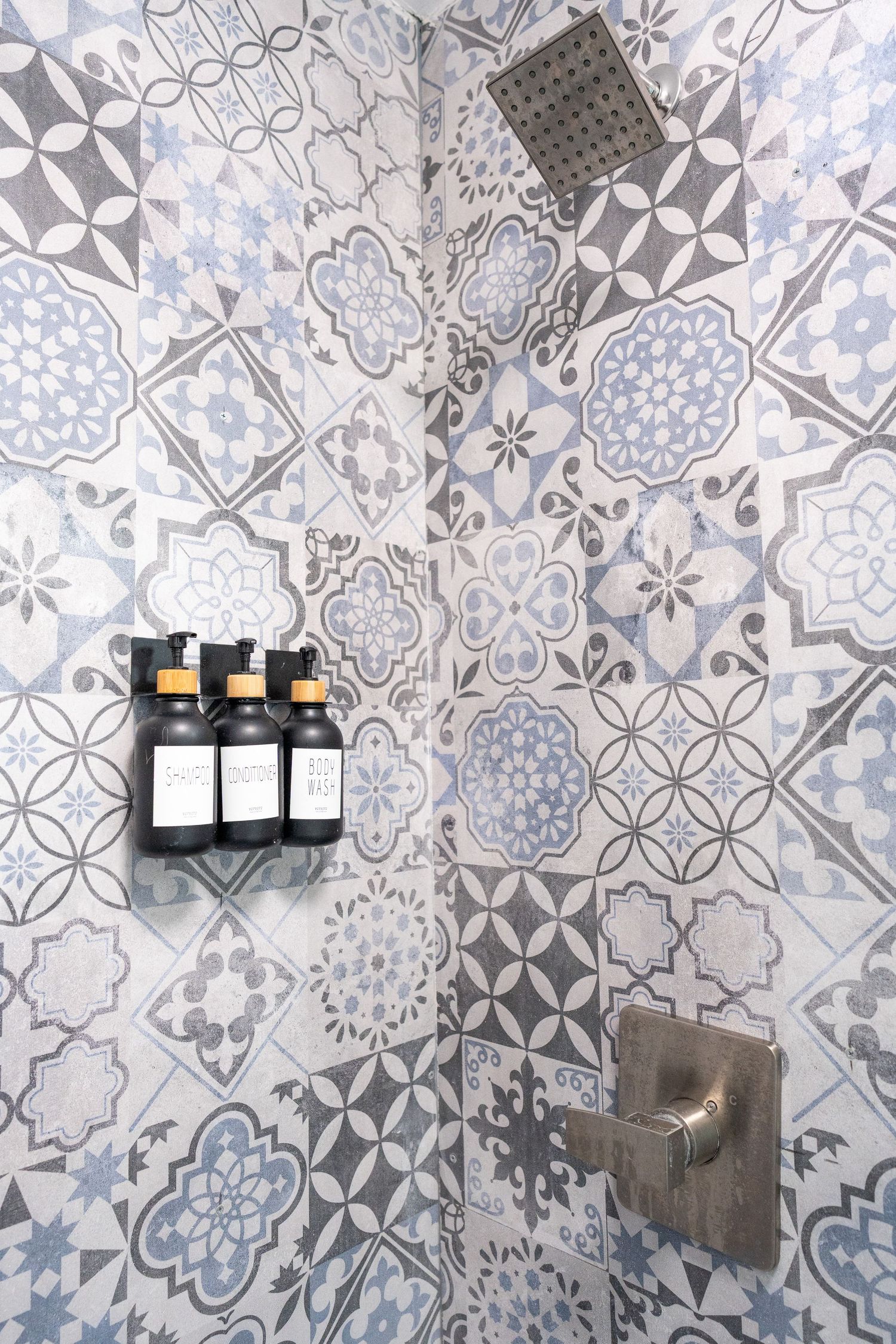 Decorative shower with blue and gray patterned mosaic tiles and rain showerhead.