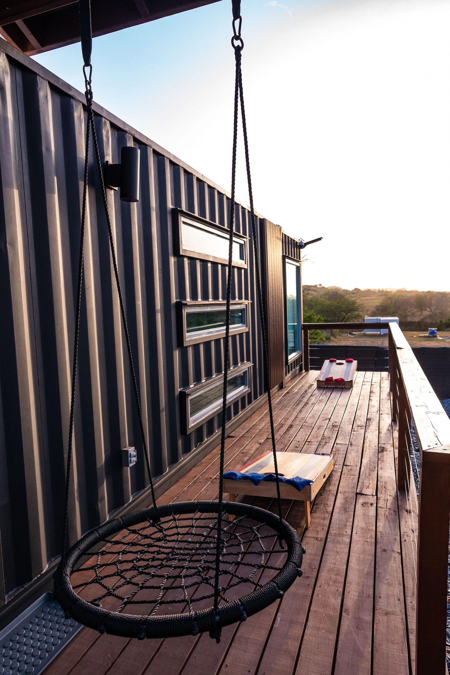 Rooftop deck of a shipping container home with a hanging nest swing and scenic landscape views.