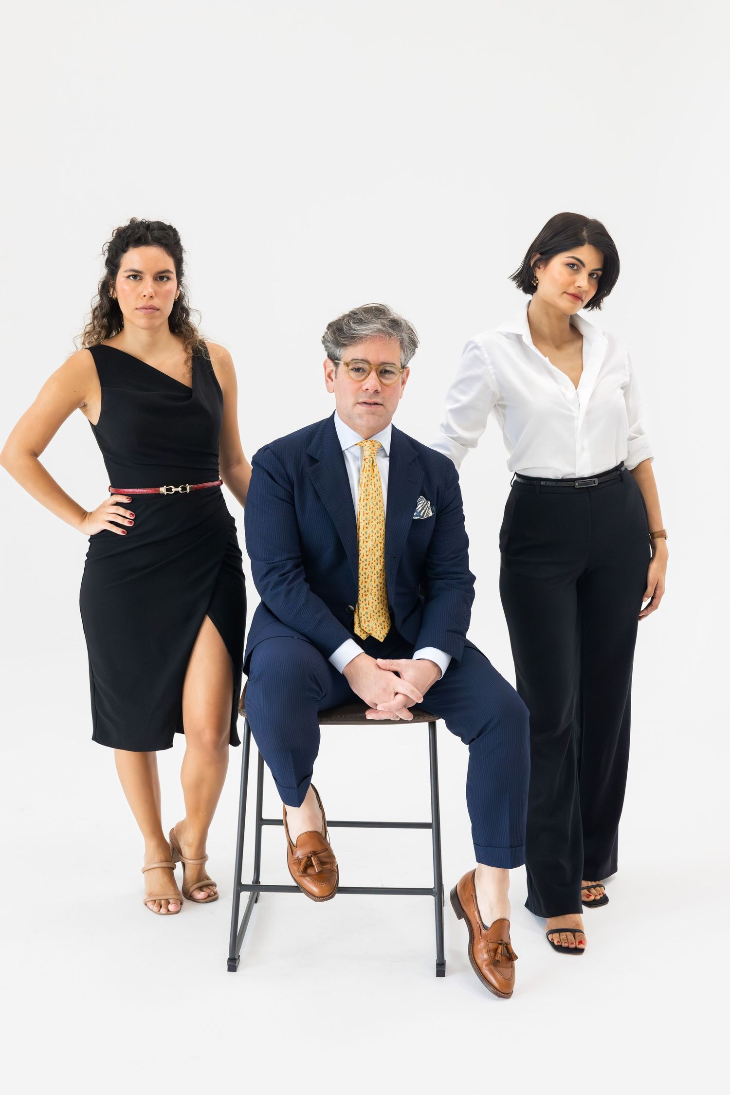 Three professionals in formal attire posing confidently against a clean white studio background.