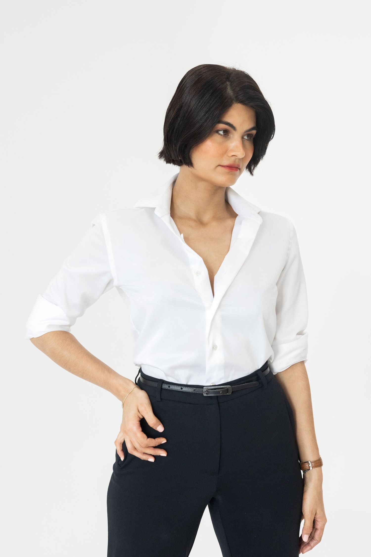 Woman in white button-up shirt and black pants posing with hand on hip.