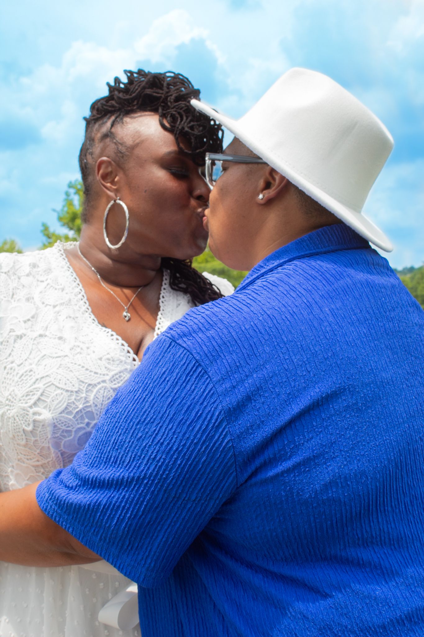 Intimate moment captured between couple in blue and white outfits against scenic background.