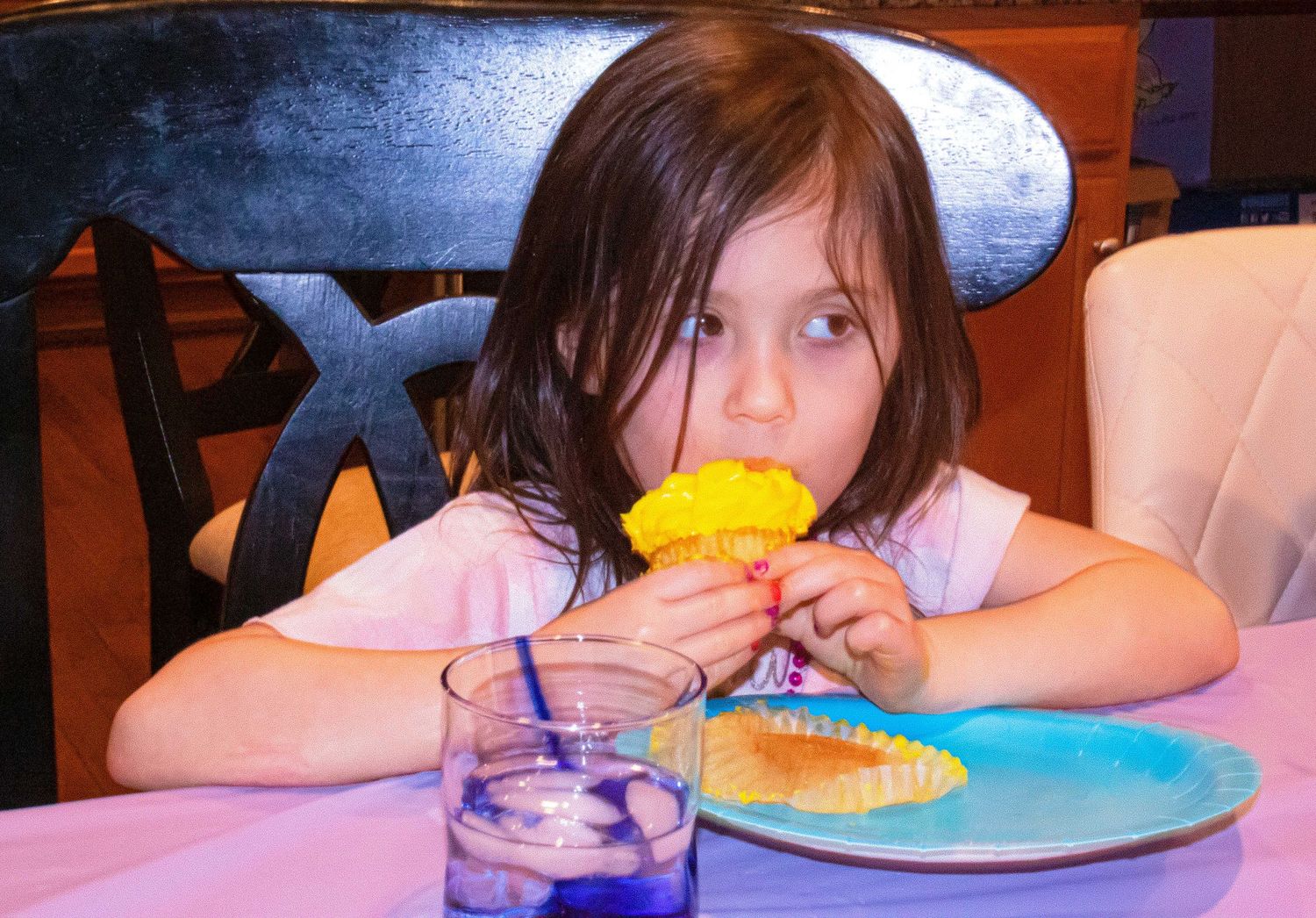 Child seated at table enjoying colorful desserts with festive lighting.