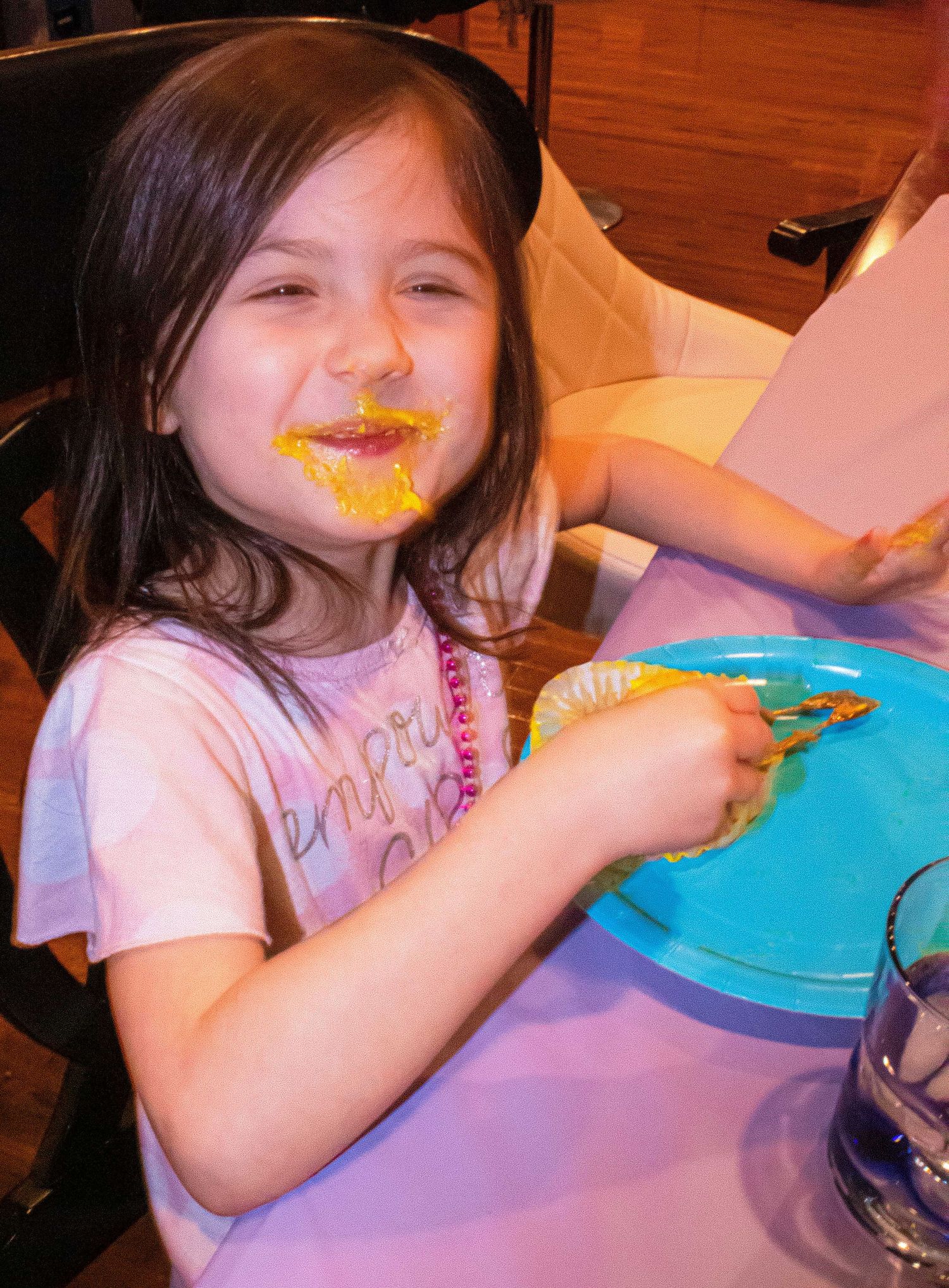 Child eating dessert at party table with bright blue plates.