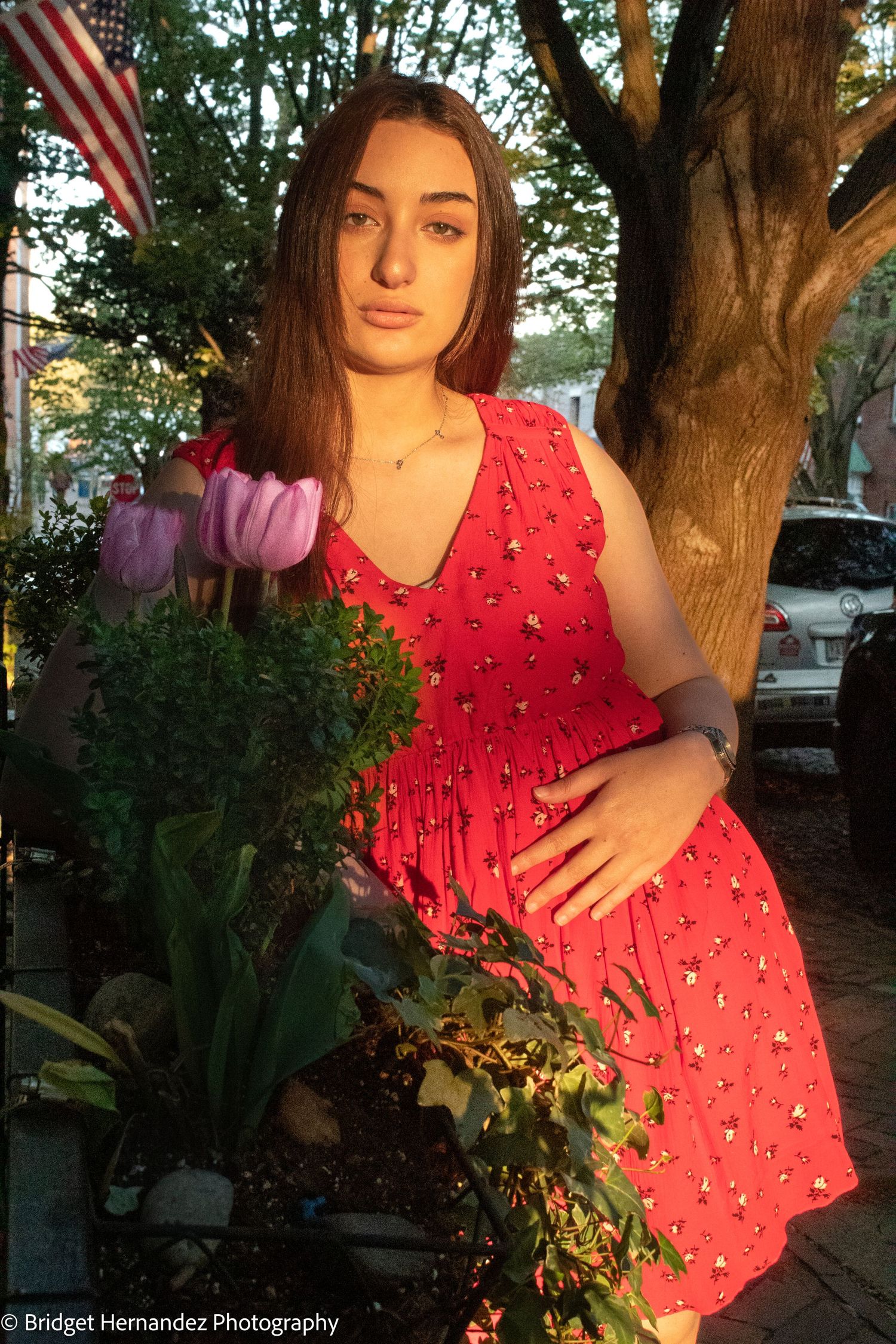 Outdoor photo session featuring a red polka dot dress against lush greenery and trees at sunset.