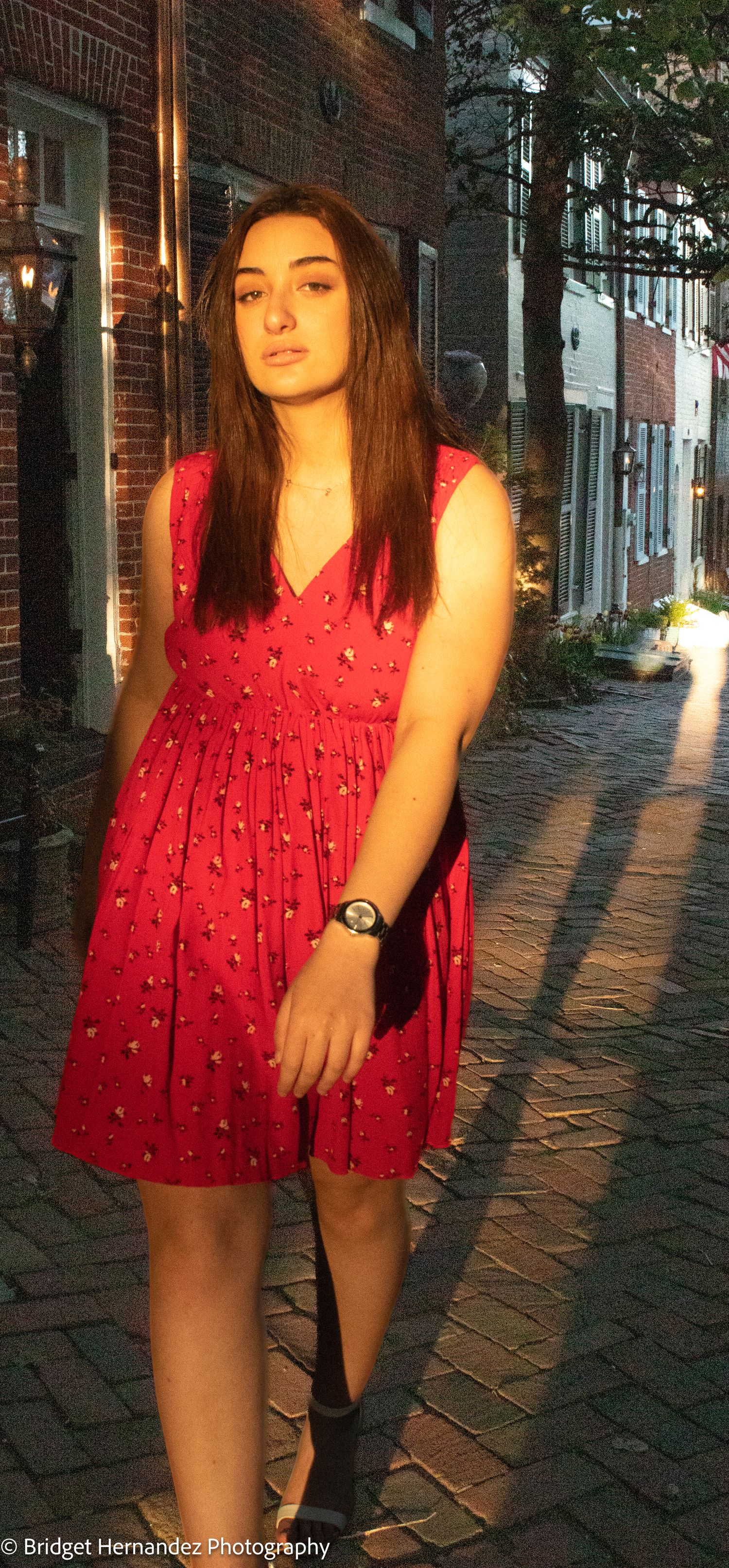 Evening photoshoot on a brick-paved street featuring a red babydoll dress.