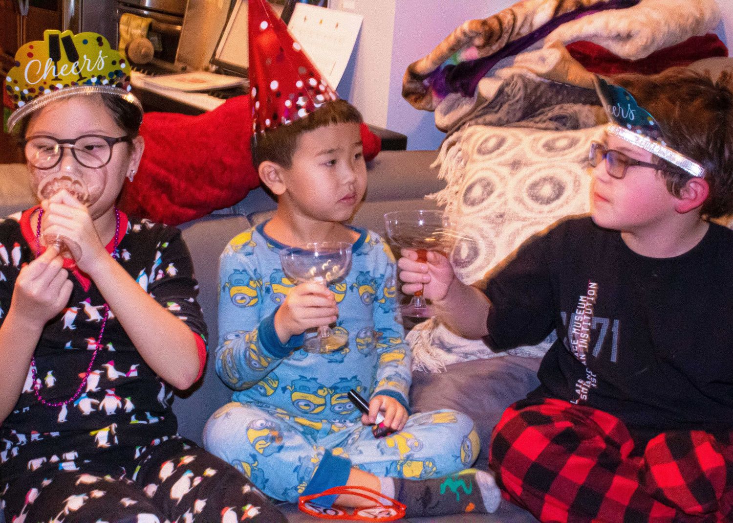 Children sitting together in party outfits with festive decorations.