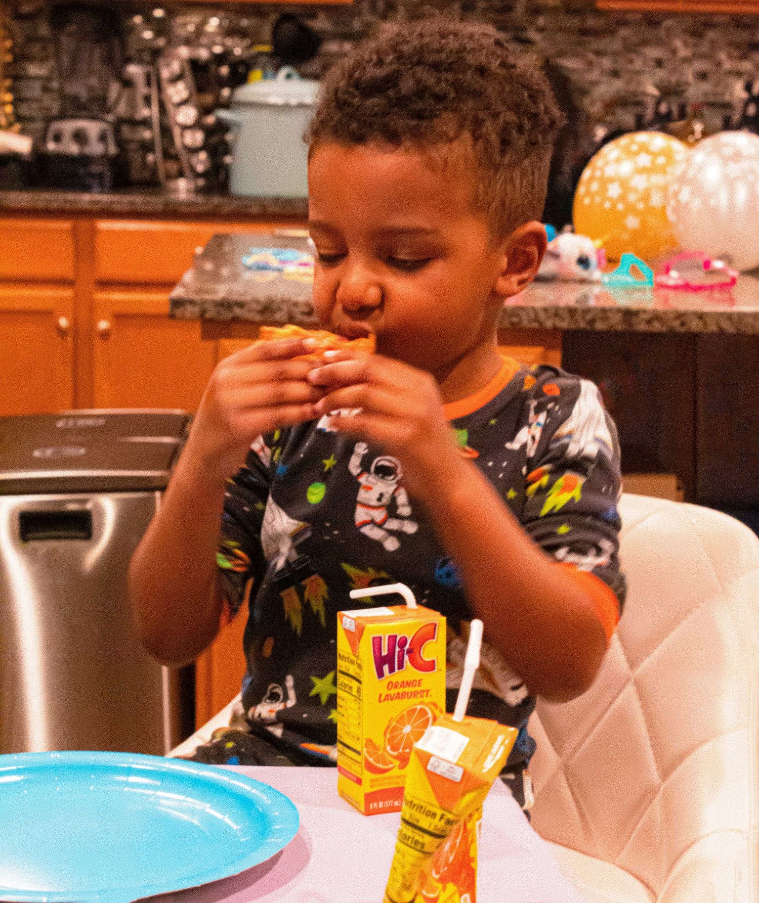 Children enjoying drinks from colorful juice boxes at a table with party decorations.