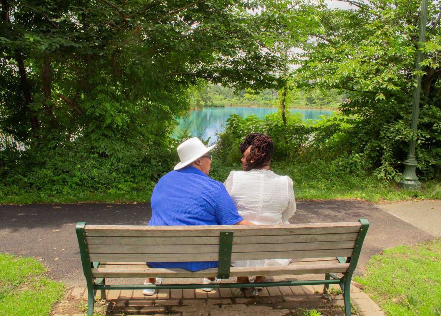 Two people relaxing on wooden bench in a peaceful garden setting.