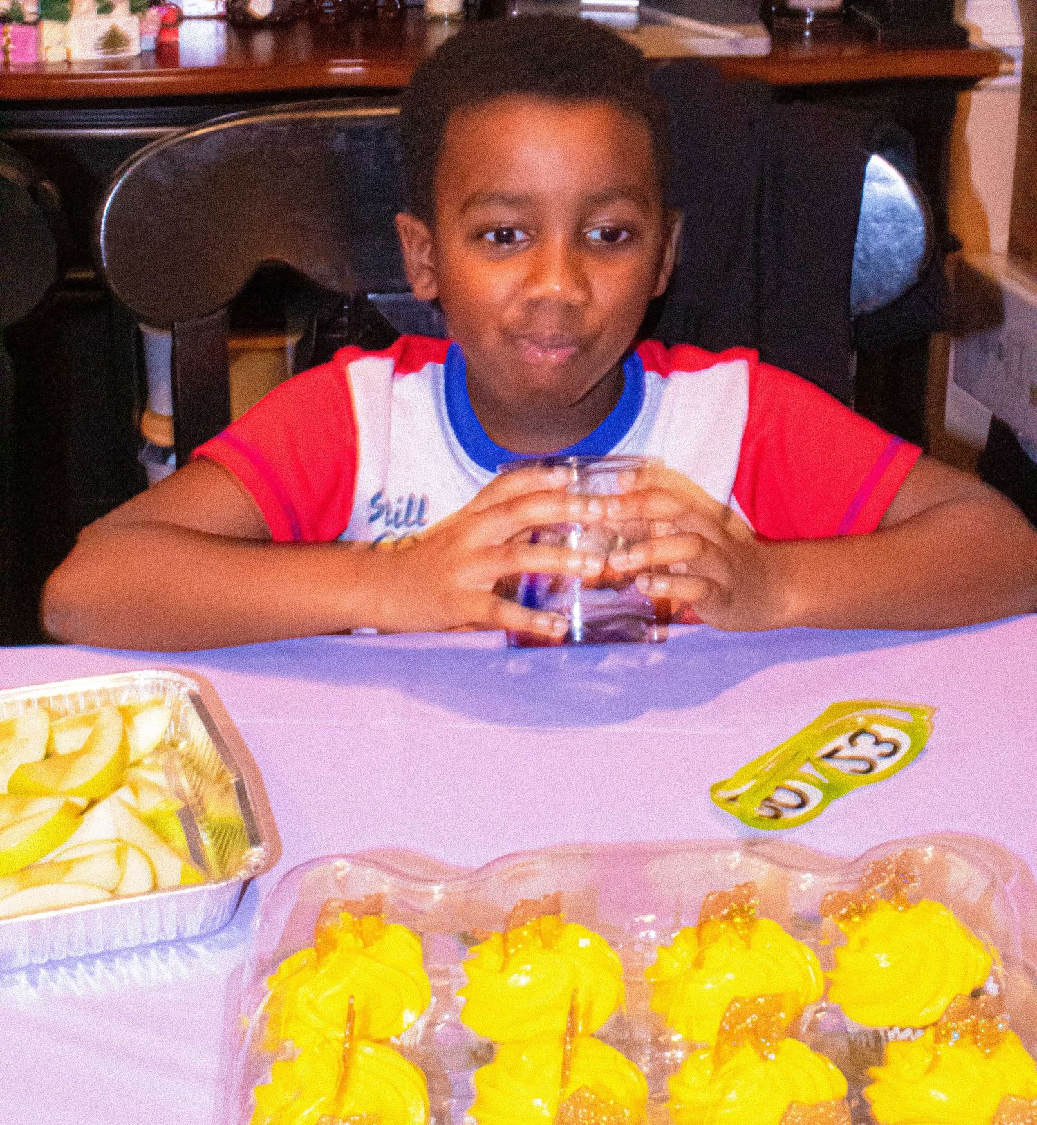 Children drinking water with yellow party treats visible on the table.