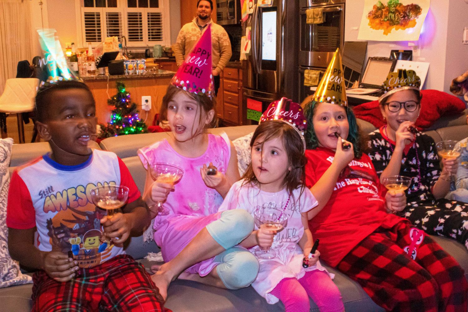 Group of kids celebrating at party with holiday decorations in background.