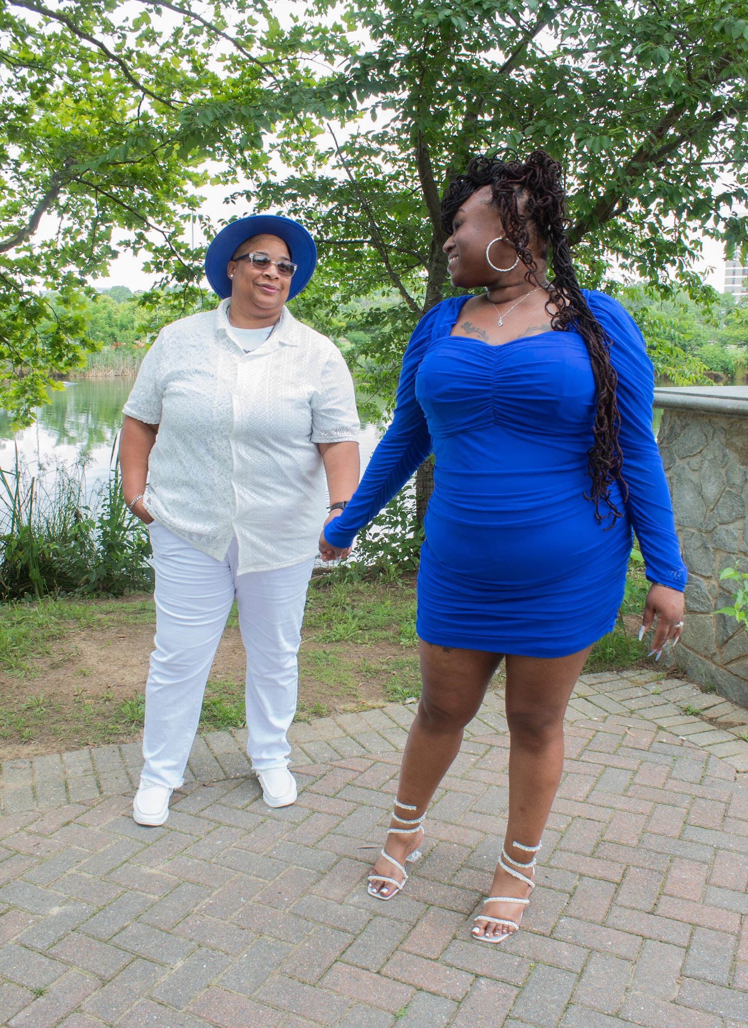 People walking together on a brick path near a pond wearing coordinated blue and white clothing.