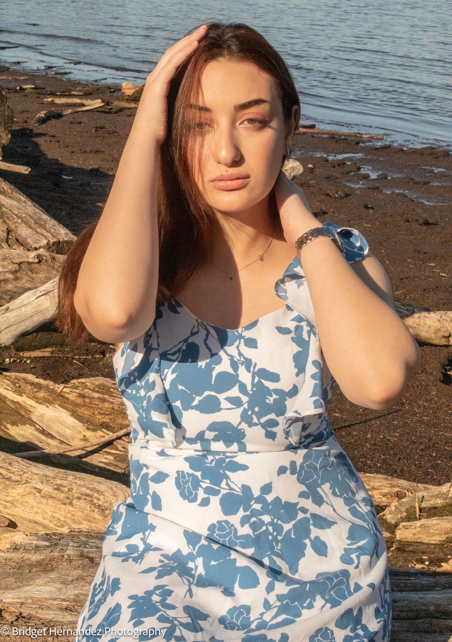 Artistic portrait featuring a blue and white floral dress by the waterfront.