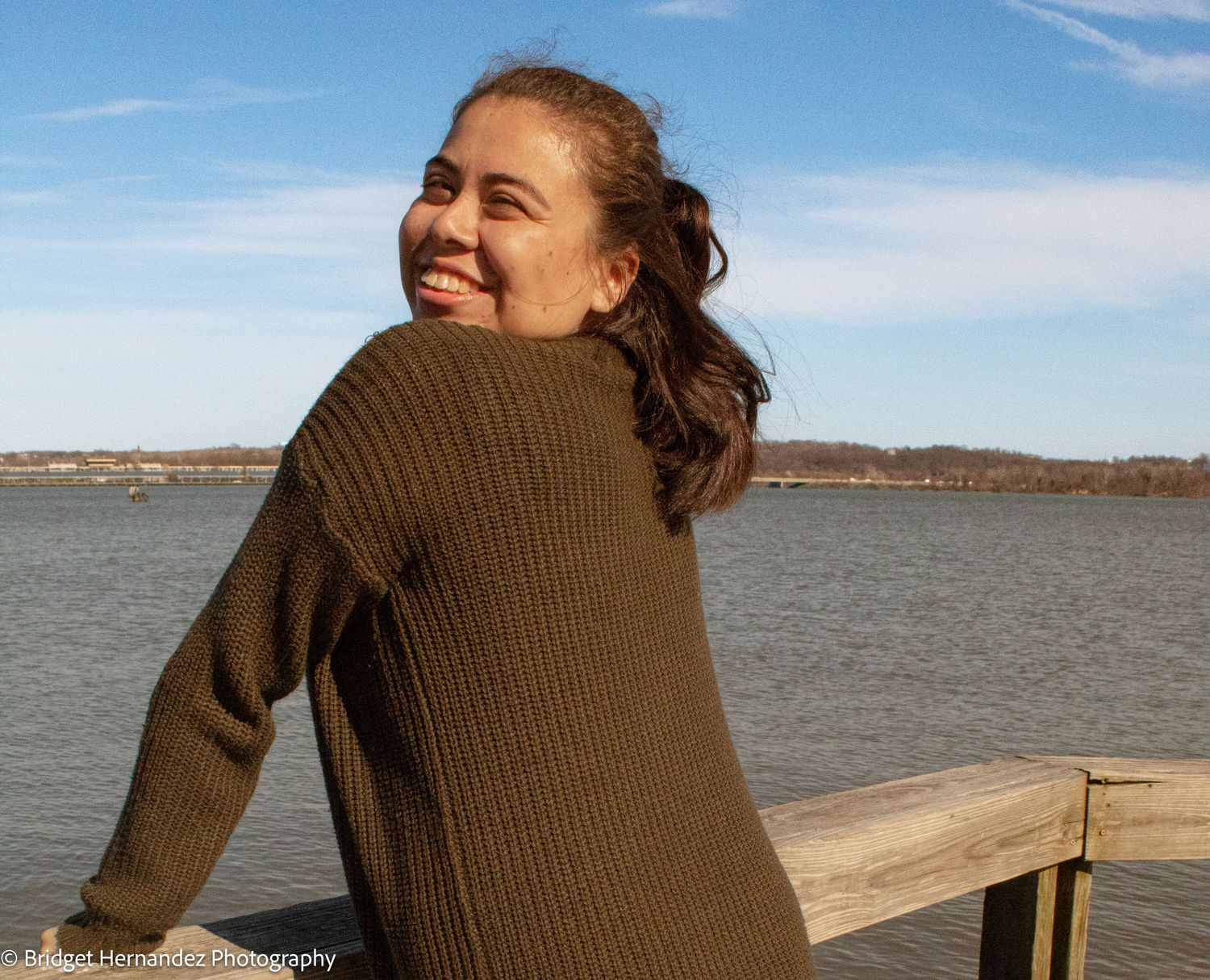 Candid waterfront photography session showing a brown sweater against blue skies.