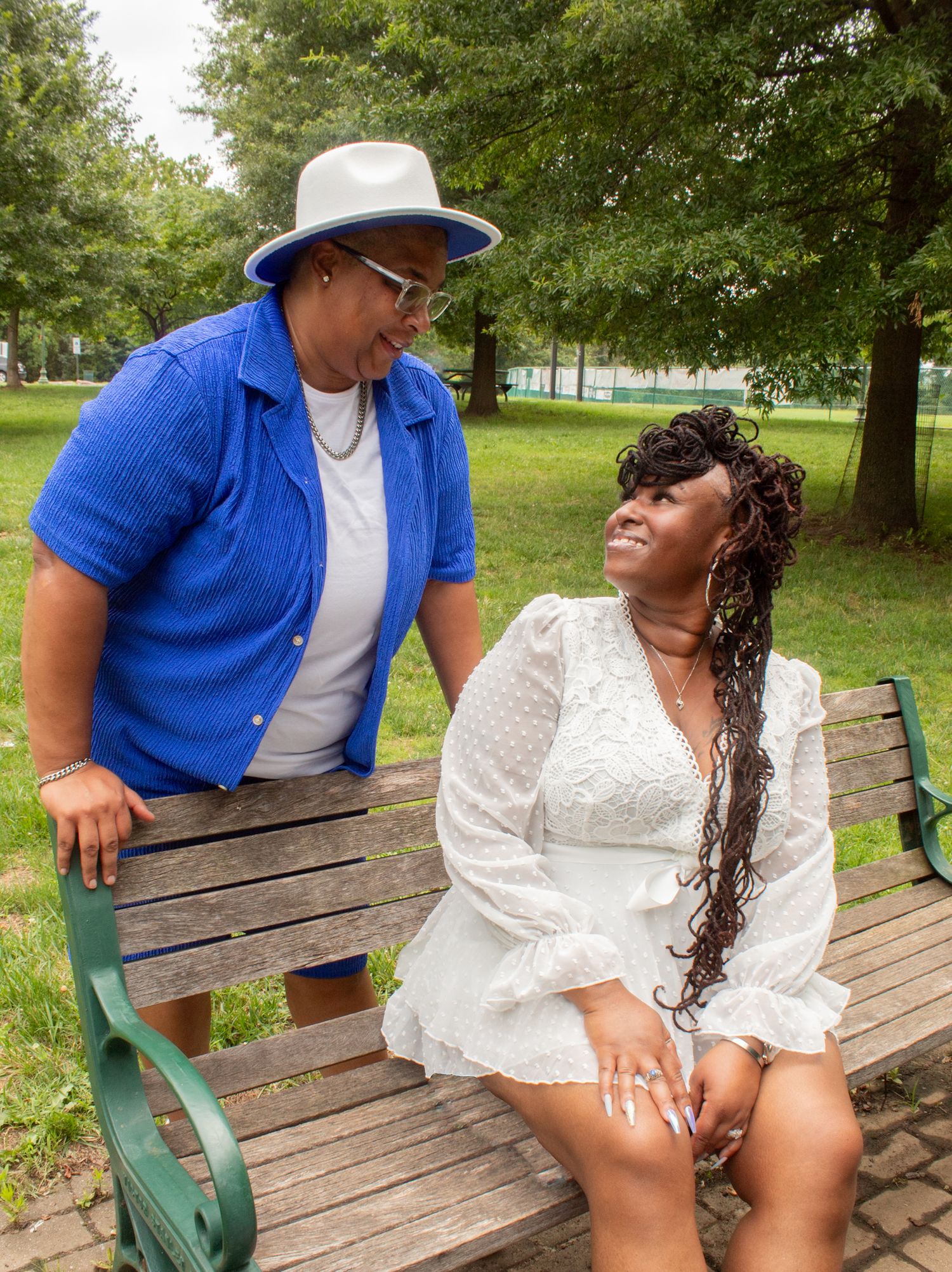 Affectionate moment shared between couple sitting on park bench in summer.