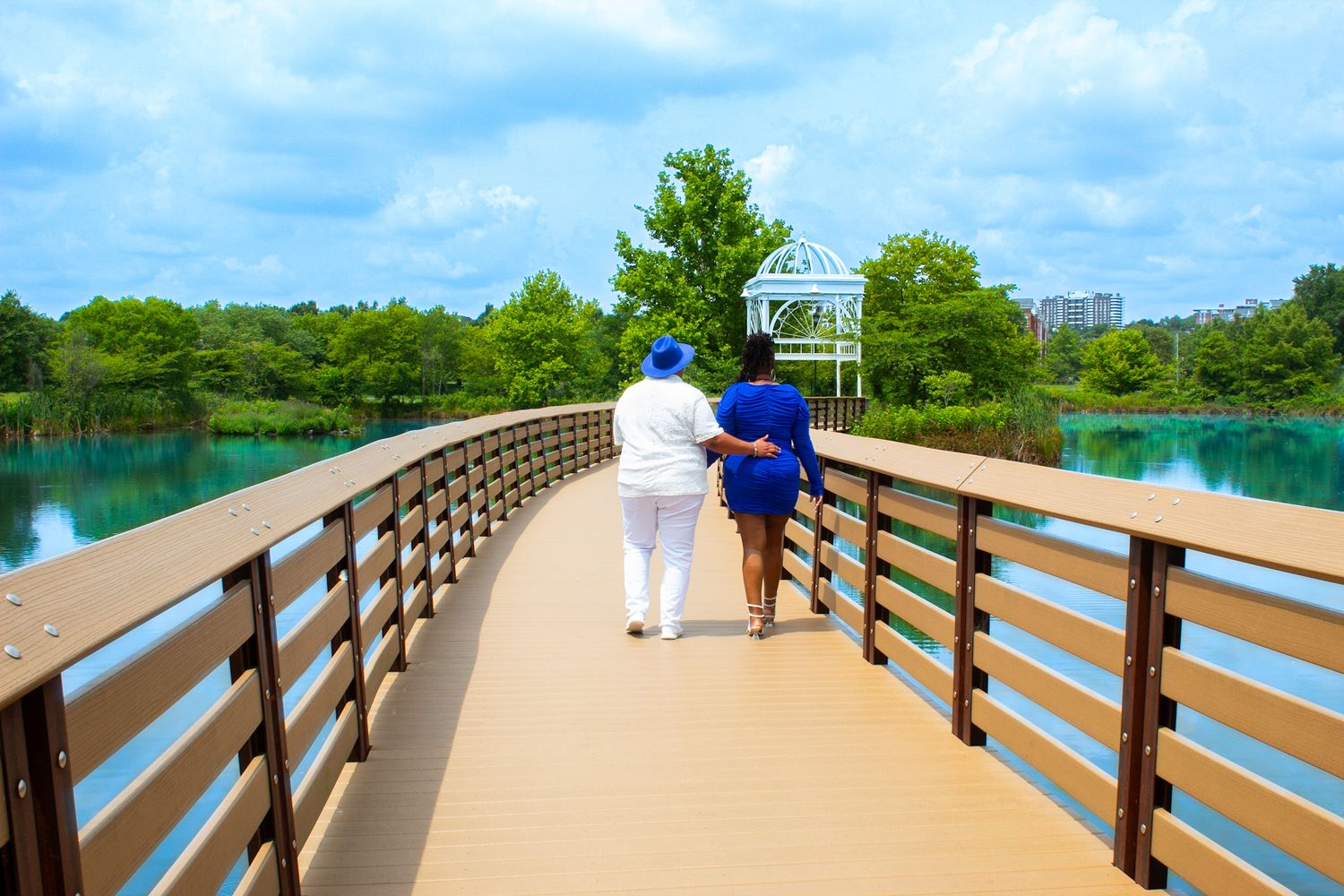 Panoramic view of wooden boardwalk with white gazebo and water views.