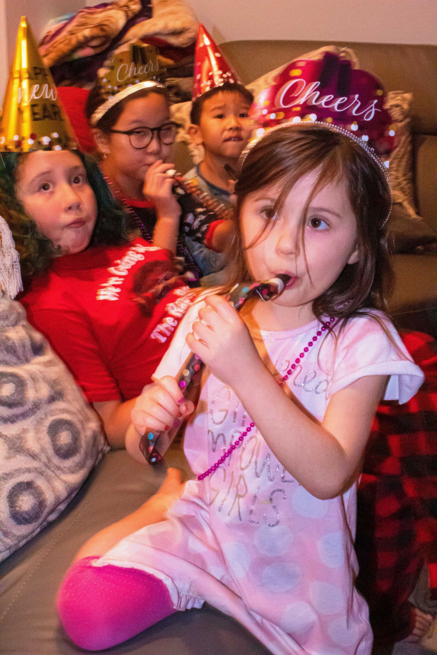 Kids sitting on couch wearing party outfits during celebration.