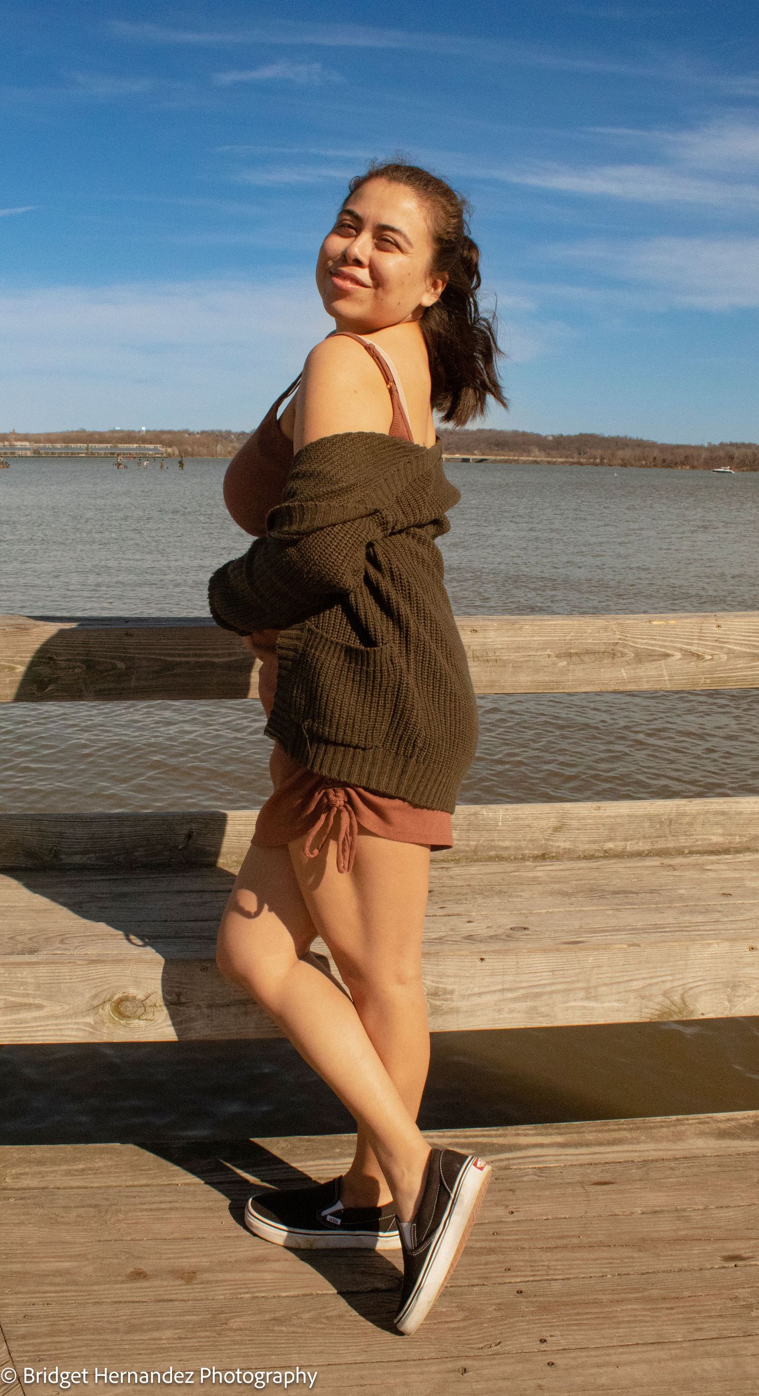 Casual outdoor photoshoot on a wooden deck overlooking a scenic lake on a sunny day.