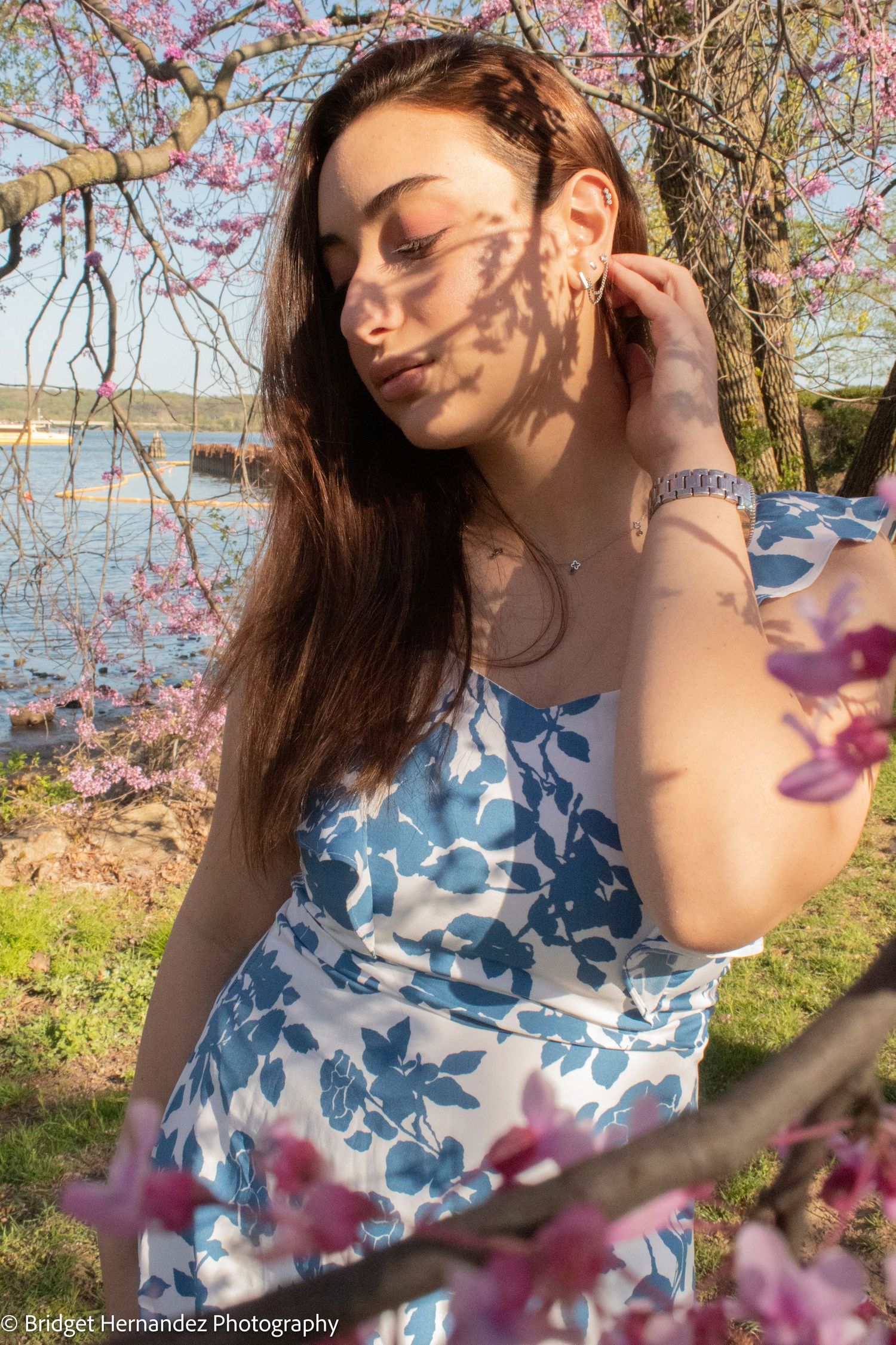 Artistic portrait with cherry blossom shadows and water view in background.