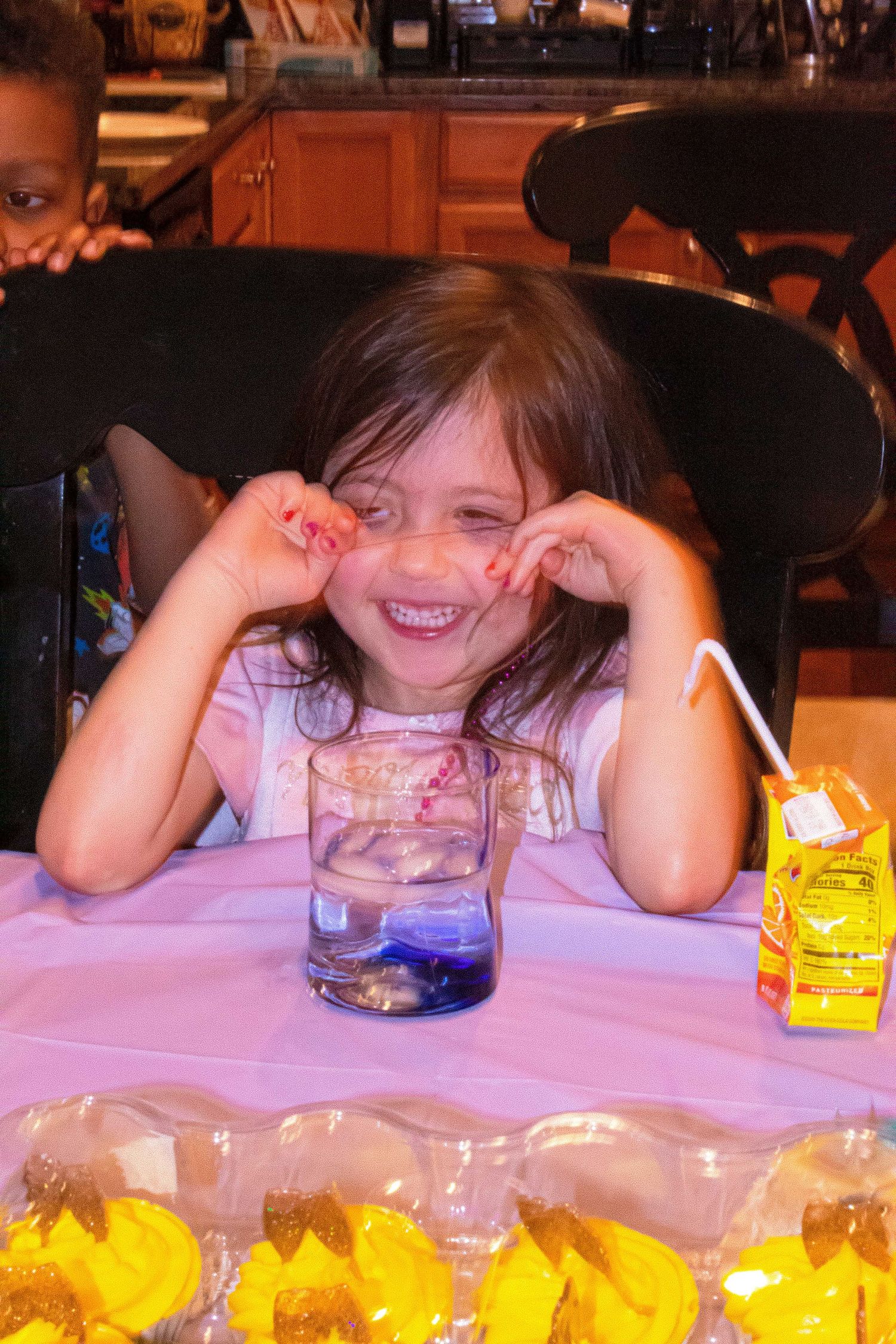 Young guest enjoying desserts at a party with yellow cupcakes.