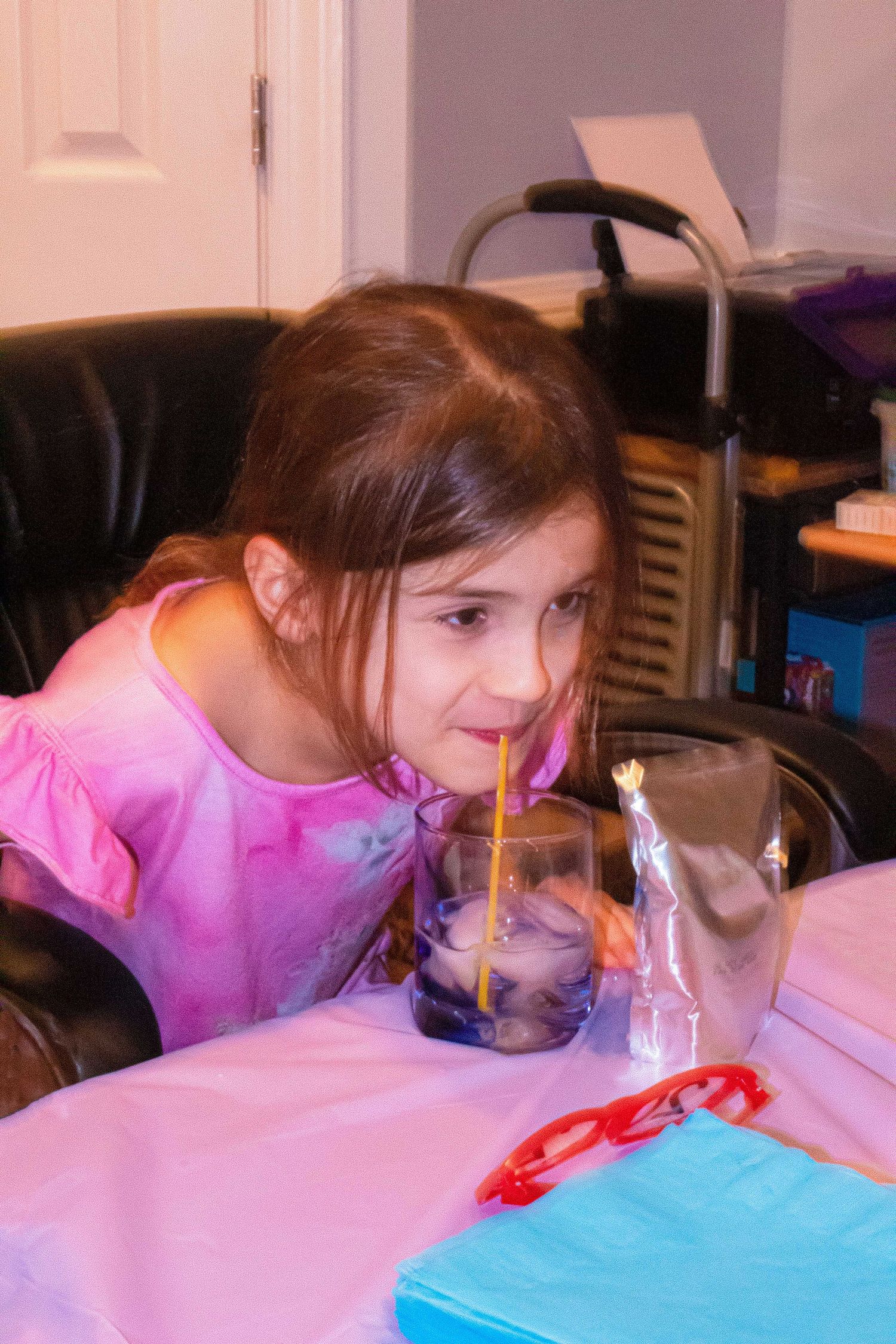 Child in pink leaning over a pink surface at the New Year's Eve party.