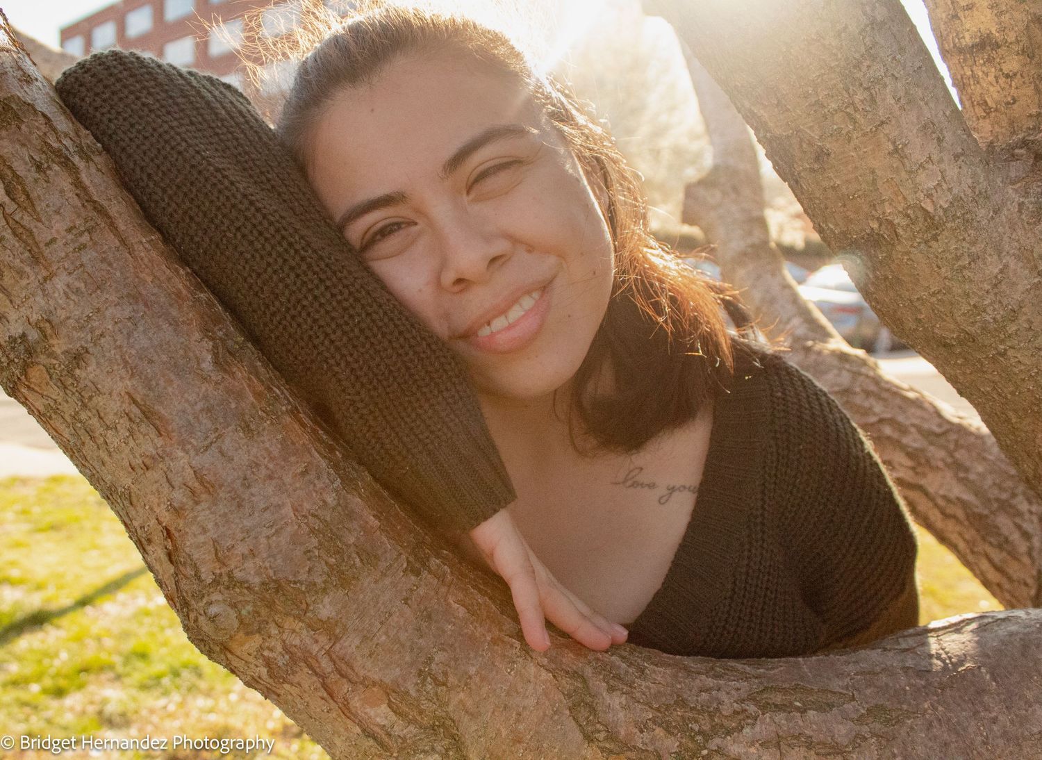 Sun-drenched portrait session against a textured tree trunk background.