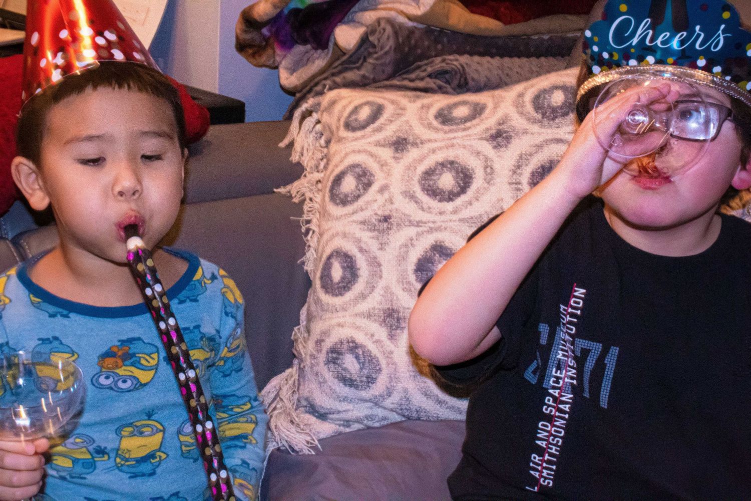 Kids blowing party horns and celebrating with decorative neon signs.