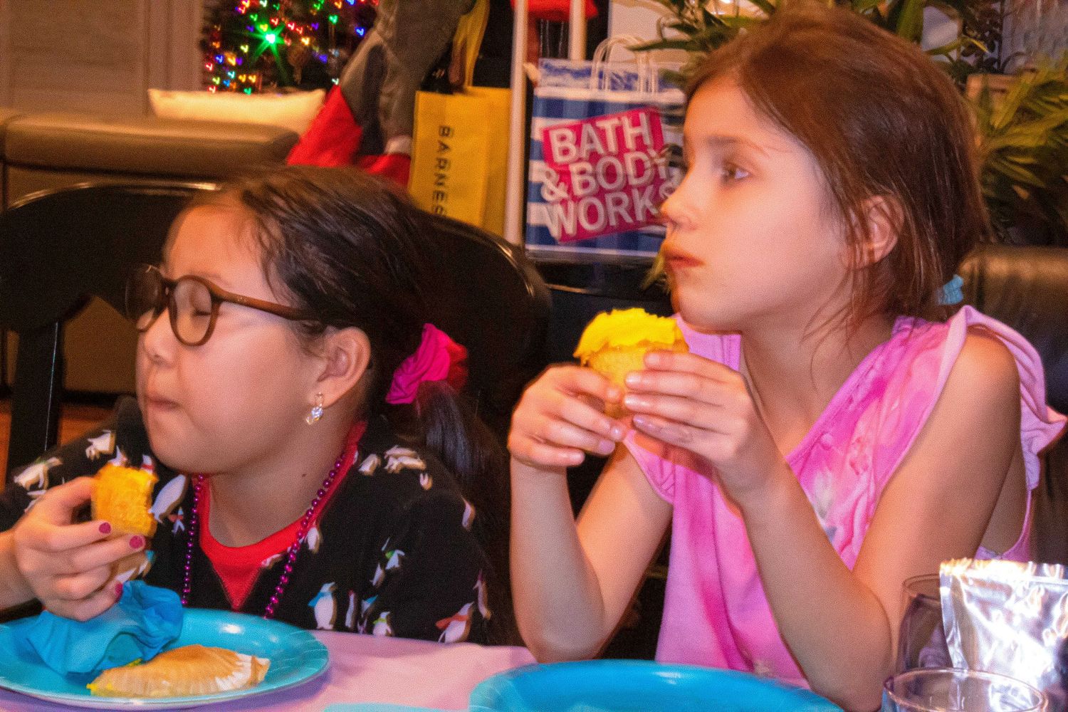 Kids sitting at decorated table eating colorful treats at celebration.