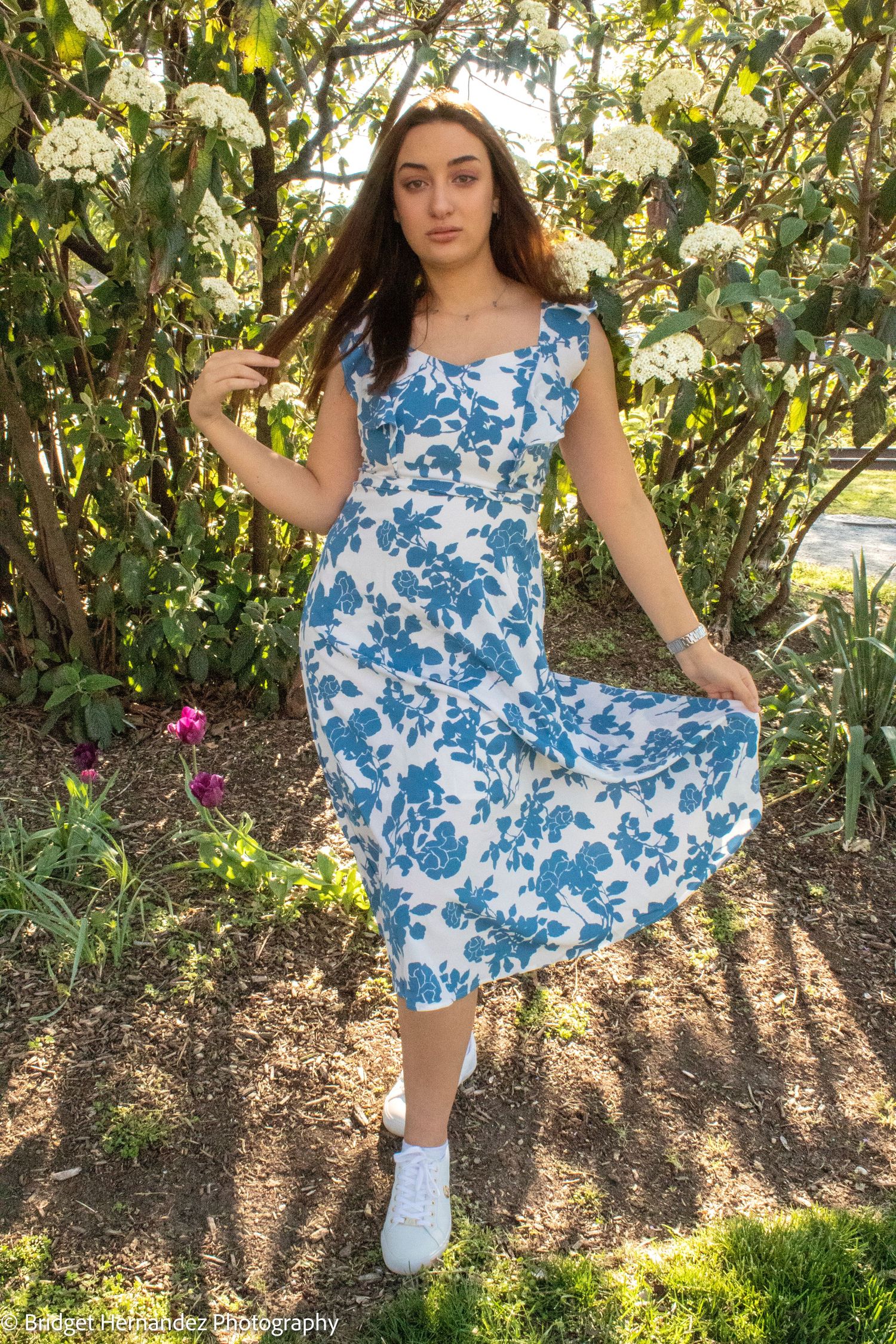 Full length fashion shot of blue and white floral dress in garden setting.
